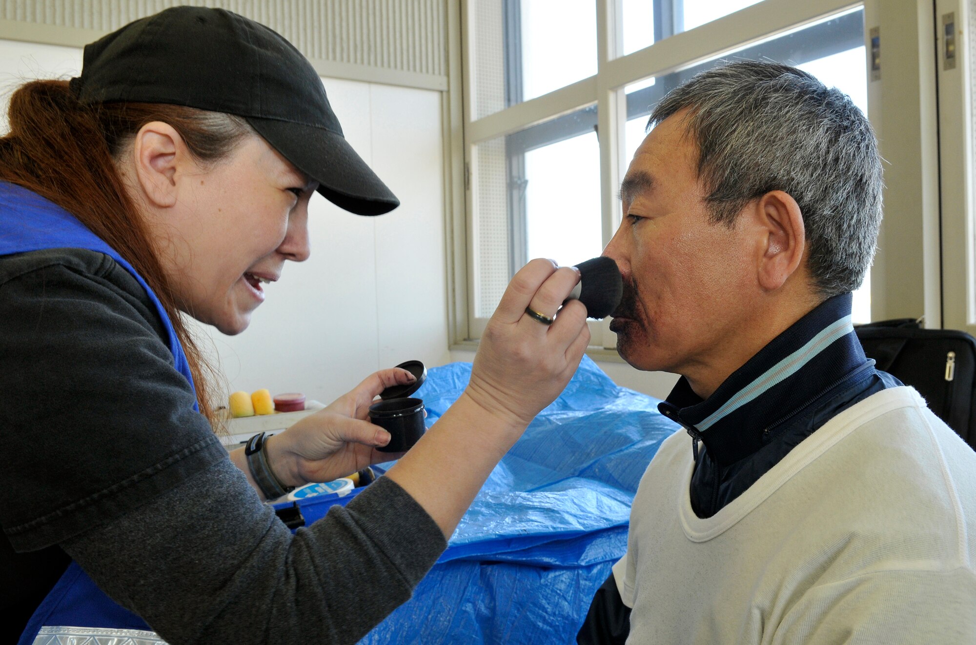 Elaine Ortiz-Harrison (left) applies moulage to Ueno Takashi, a Japanese volunteer for an accident exercise Feb. 23, 2011, in Misawa City, Japan. Moulage is a make-up technique used to create realistic injuries on exercise victims. Ms. Ortiz-Harrison is a volunteer make-up artist assigned to the 35th Medical Group. (U.S. Air Force photo/Tech. Sgt. Phillip Butterfield/) 