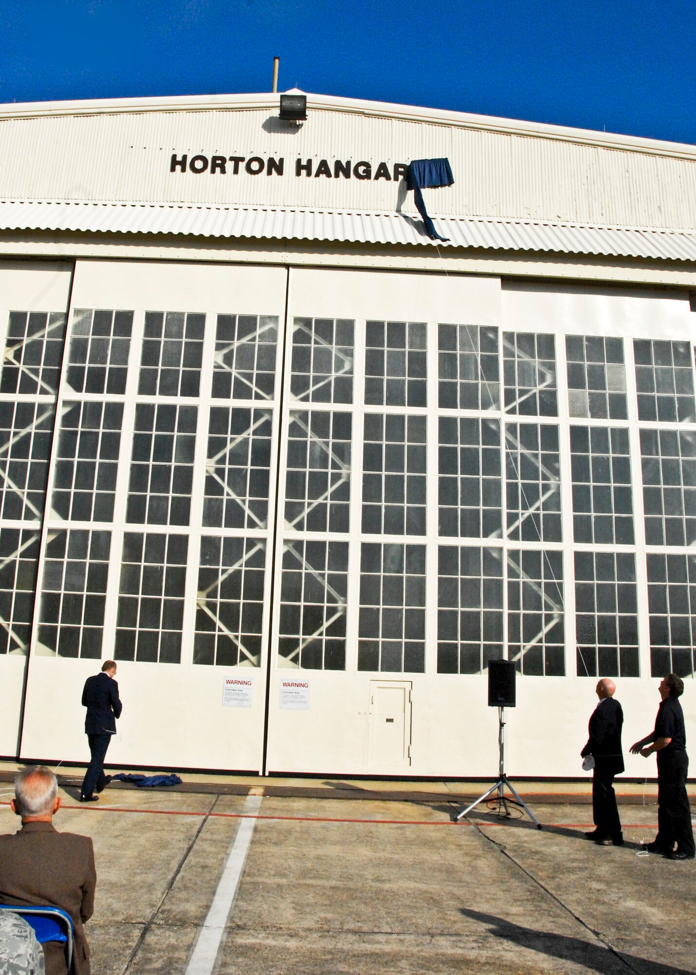 Lt. Col. (ret.) Dick Cole and Master Sgt. (ret.) Wes Fields unveil the newly named Horton Hangar, atop the Horton J-Primes Test Facility Feb. 23 at Eglin Air Force Base, Fla.  The hangar was named for Master Sgt. Edwin Horton, one of the original “Doolittle’s Raiders,” who, along with Cole, was part of a precedence-setting bombing mission of the Japanese mainland in World War II.  Sergeant Horton served in the Army, Air Force and civil service for more than 45 years.  (U.S. Air Force photo/Kevin Gaddie)  