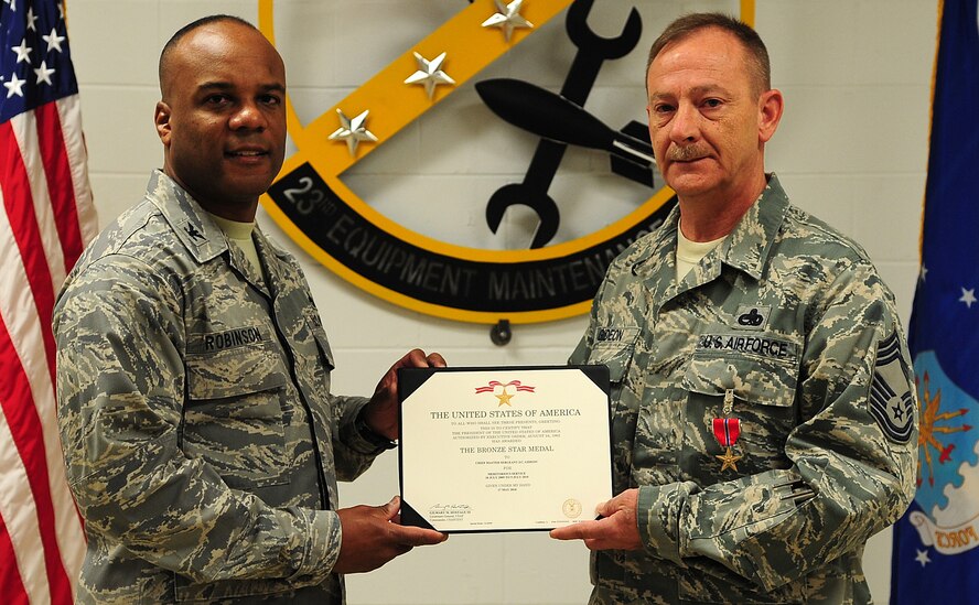 MOODY AIR FORCE BASE, Ga.-- Col. Neal Robinson, 23rd Maintenance Group commander, awards Chief Master Sgt. J.C. Gideon, 23rd Equipment Maintenance Squadron chief enlisted manager, with the Bronze Star Medal certificate Feb. 25. Chief Gideon earned the medal for meritorious service from July 10, 2009 to July 9, 2010. (U.S. Air Force photo/Senior Airman Stephanie Mancha)(RELEASED)