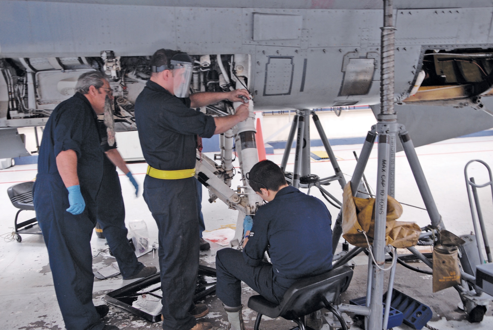 Civilian Ron Dulaney, left, Senior Airman Anthony Griffin, middle, and Airman 1st Class Jacob Gonzalez, 56th Equipment Maintenance Squadron phase team members, dismantle the landing gear at phase dock three on February 17th.  Fixing the landing gear takes place on the second and third days of the phase.  (U.S. Air Force photo/Aiman David Owsianka)