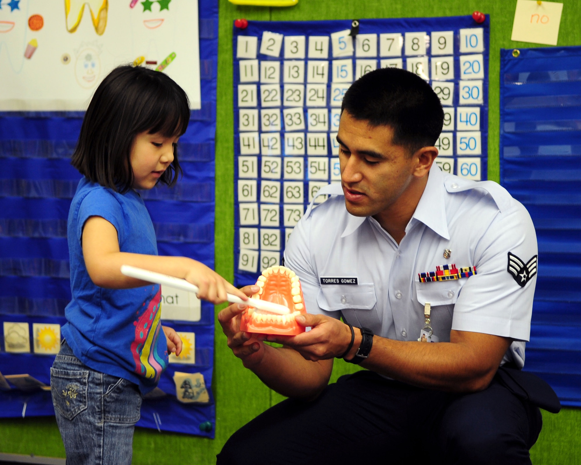 DAVIS-MONTHAN AIR FORCE BASE, Ariz. - Senior Airman Job Torres-Gomez, 355th Dental Squadron dental assistant, shows a student from Borman Elementary School the proper technique used when brushing teeth as part of the National Children’s Dental Health month here Feb. 18. Airmen from the 355th DS visited the school to educate the children on good oral hygiene. (U.S. Air Force photo/Airman 1st Class Jerilyn Quintanilla)