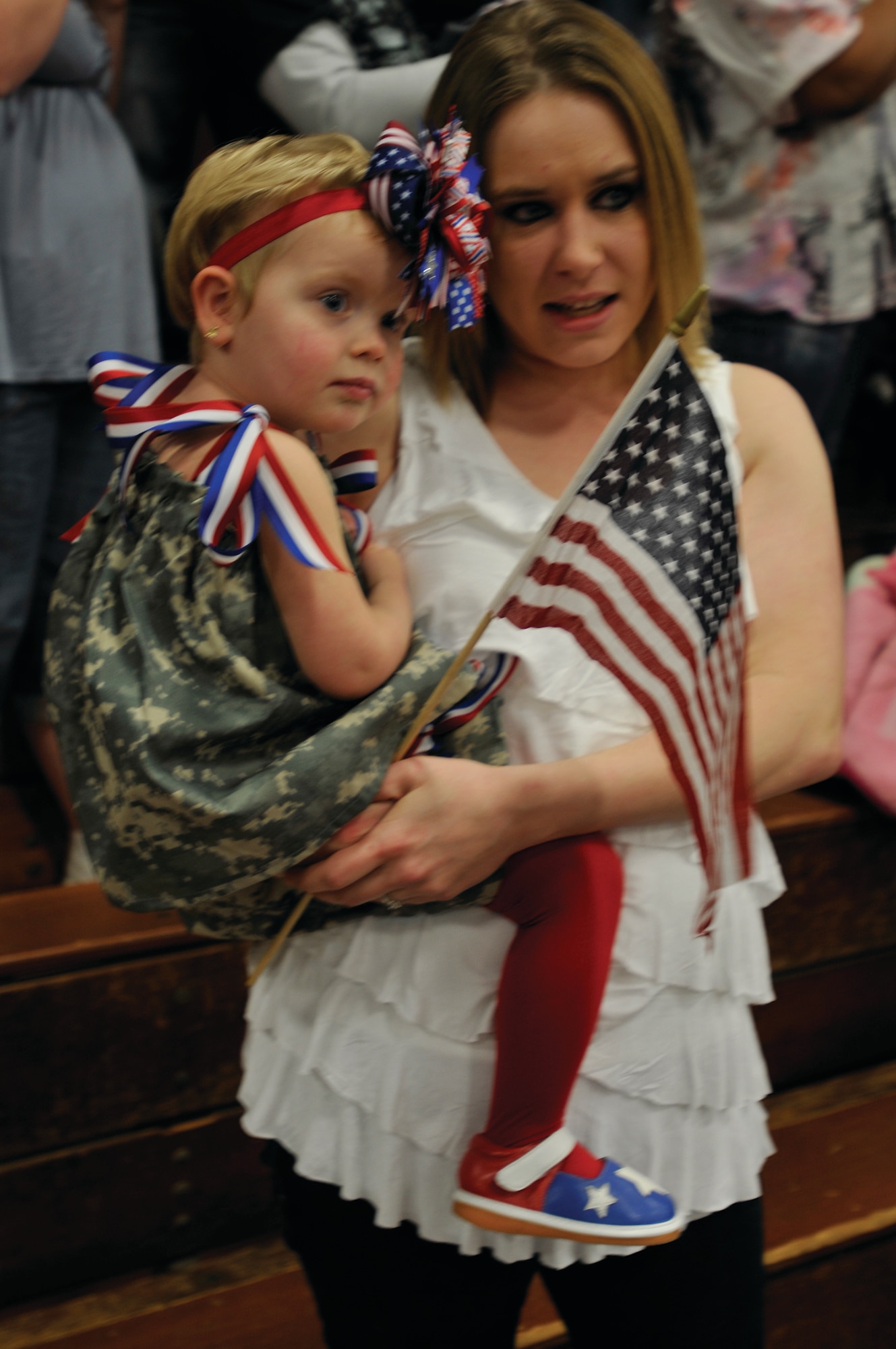 Lisa Miller holds daughter, Madison, as they watch Sgt. Neal Miller march into Anderson Field House during the 7th Sustainment Brigade’s welcome home ceremony for Soldiers of the 510th Human Resources Company, Special Troops Battalion, and the 567th Inland Cargo Transfer Company, 24th Transportation Battalion. This marks the third deployment for Sergeant Miller. Lisa and daughters Madison and Kenzee greeted him home with an abundance of hugs and smiles. (Photo by Sgt. 1st Class Kelly Jo Bridgwater)

