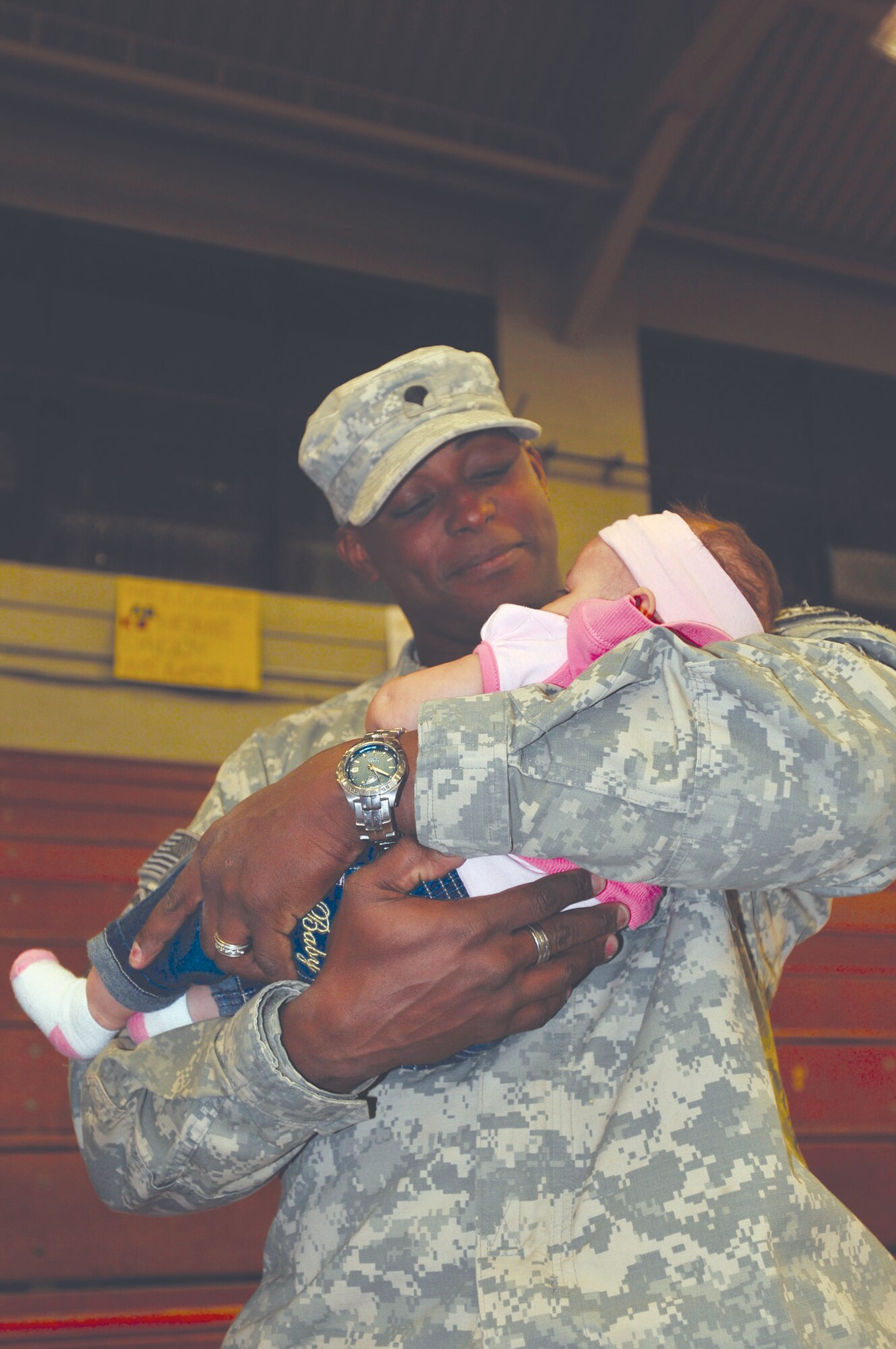 Spc. Mark Ayers holds his 3-month-old daughter for the first time upon his return home from Afghanistan. Specialist Ayers, who is assigned to the 567th ICTC, 24th Transportation Battalion, stood in the bleachers at Anderson Field House Wednesday night lost in the gaze of his newborn daughter’s eyes. (Photo by Sgt. 1st Class Kelly Jo Bridgwater)


