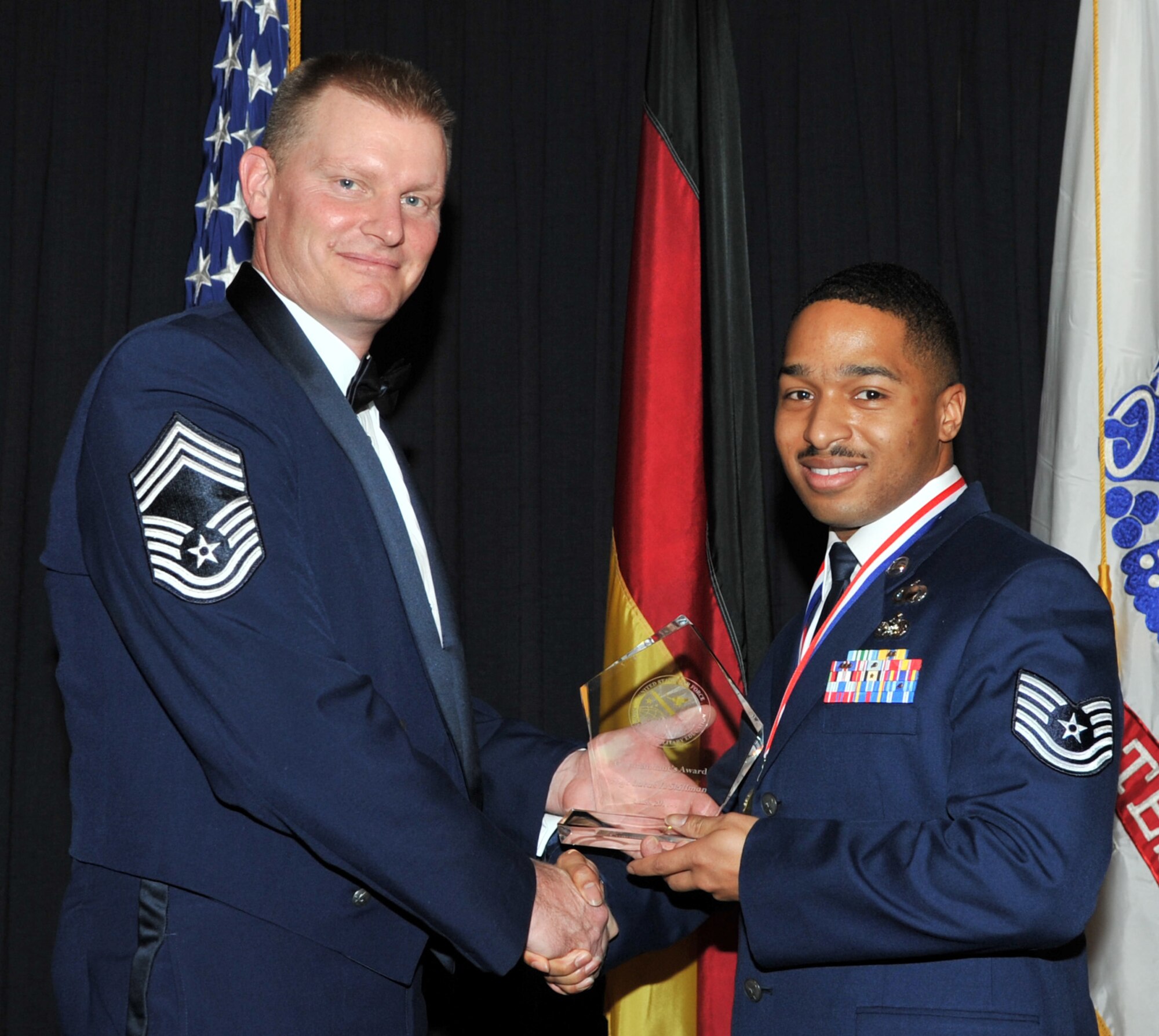 Chief Master Sgt. David Lawrence, the commandant of the Kisling Noncommissioned Officer Academy, presents the Commandant’s Award to Tech. Sgt. Lucas Skillman, Feb. 10, 2011, at Ramstein Air Base, Germany.  The Commandant’s Award is presented to the student who, in the commandant’s judgment, made the most significant contribution to the overall success of the class. (U.S. Air Force photo by Senior Airman Caleb Pierce/Released)