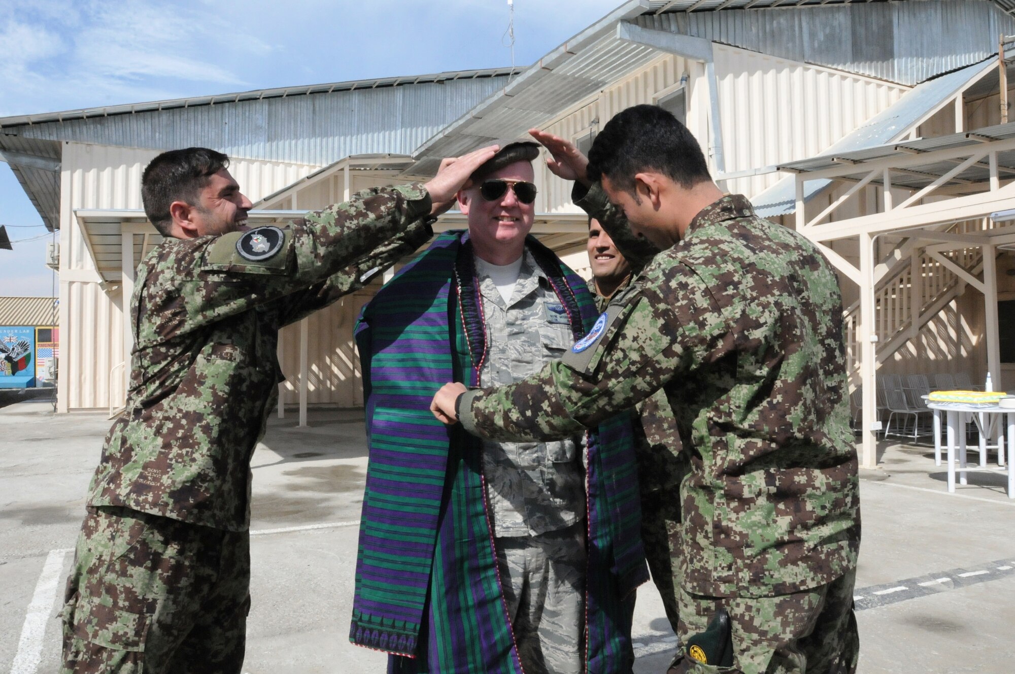 KABUL, Afghanistan - Lt. Col. Wayne McCaskill is recognized by Afghan Air Force lieutenants and their fellow cadre members with mementos,an Afghan formal robe and a Massoud hat, to remember their time in Afghanistan prior to their departure. (U.S. Navy photo by Mass Communications Specialist Jared E. Walker)