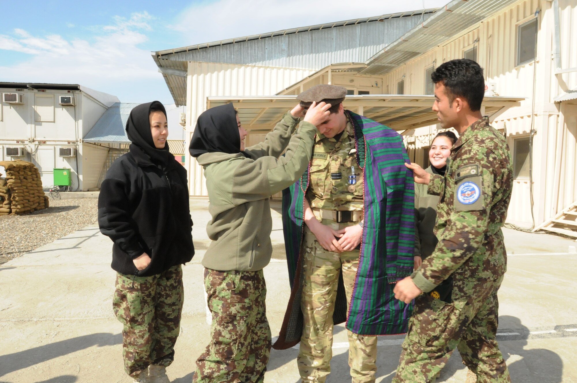 KABUL, Afghanistan - Royal Air Force Flight Lieutenant John Parry is recognized by Afghan Air Force lieutenants and their fellow cadre members with mementos,an Afghan formal robe and a Massoud hat, to remember their time in Afghanistan prior to their departure. (U.S. Navy photo by Mass Communications Specialist Jared E. Walker)