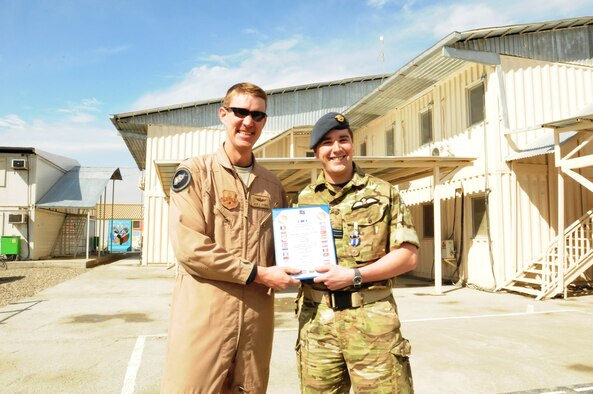 KABUL, Afghanistan - Royal Air Force Flight Lieutenant John Parry is recognized by Afghan Air Force lieutenants and their fellow cadre members with mementos,an Afghan formal robe and a Massoud hat, to remember their time in Afghanistan prior to their departure. (U.S. Navy photo by Mass Communications Specialist Jared E. Walker)