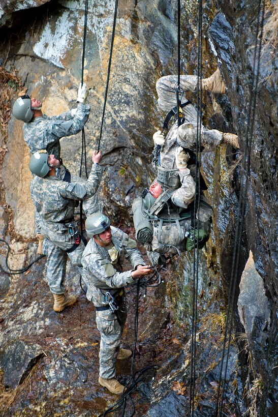 Army Rangers assist other students by holding their rappelling ropes as they lower themselves down the side of a 60-foot rock face on Camp Frank D. Merrill, in Dahlonega, Ga., Feb. 20, 2011.