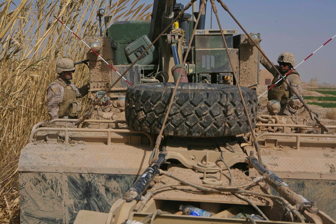 Cpl. Corey J. Hiles, a wrecker operator and Lance Cpl. Anthony Henriquez, a motor transportation mechanic with Support Company, Combat Logistics Battalion 3, 1st Marine Logistics Group (Forward) recovers a mine roller off of an immobilized Mine Resistant Ambush Protected vehicle in Trek Nawa, Afghanistan, Feb. 25. The vehicle became stuck after a portion of the road it was travelling on gave out. The recovery was in support of 2nd Battalion, 8th Marine Regiment.