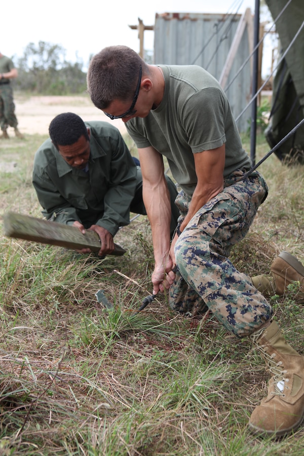 Cpl. Ryan Hildreth, motor transportation operator with Logistics Combat Element, Security Cooperation Task Force and Lance Cpl. Cain L. Kenrick, an infantryman with Belize Defense Force work together to set up a tent for the gas chamber, Feb. 27, conducted in support of Amphibious Southern Partnership Station 2011. (U.S. Marine Corps photo by Cpl. Brittany J. Kohler)