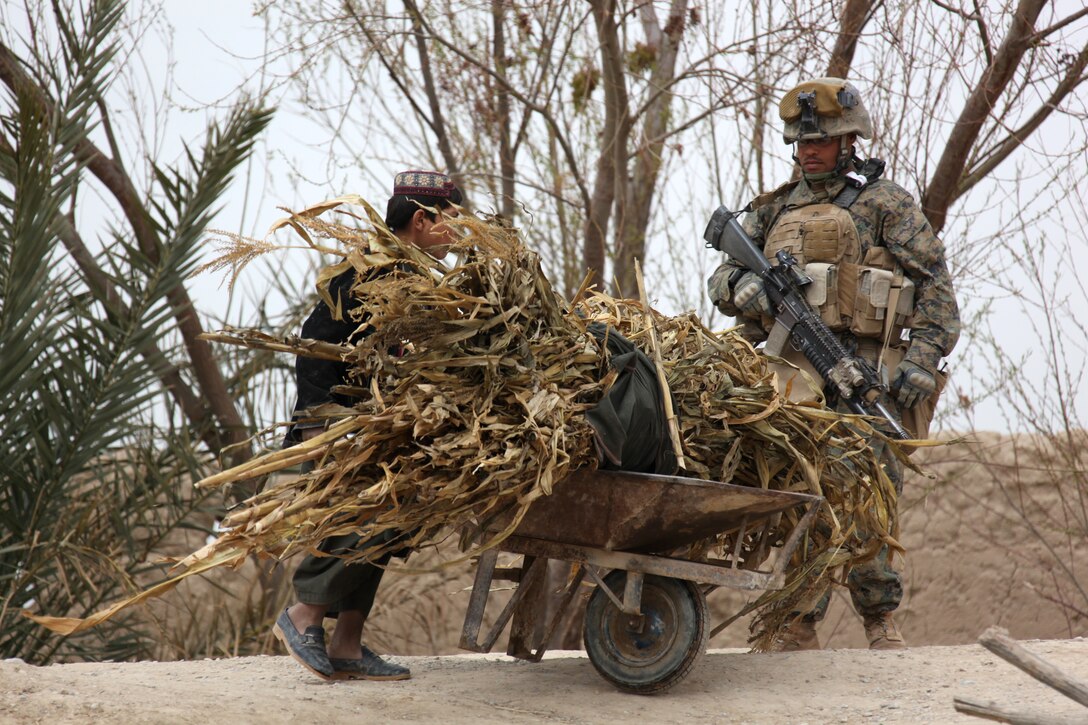 U.S. Marine Corps Cpl. William Moore, a team leader with 2nd Platoon, Company I, Battalion Landing Team 3/8, 26th Marine Expeditionary Unit, Regimental Combat Team 8, watches an Afghan boy move animal fodder at a vehicle check point at a bridge crossing the Nahr-e Saraj canal in Helmand province, Afghanistan, Feb. 27, 2011. Elements of 26th Marine Expeditionary Unit deployed to Afghanistan to provide regional security in Helmand province in support of the International Security Assistance Force.
