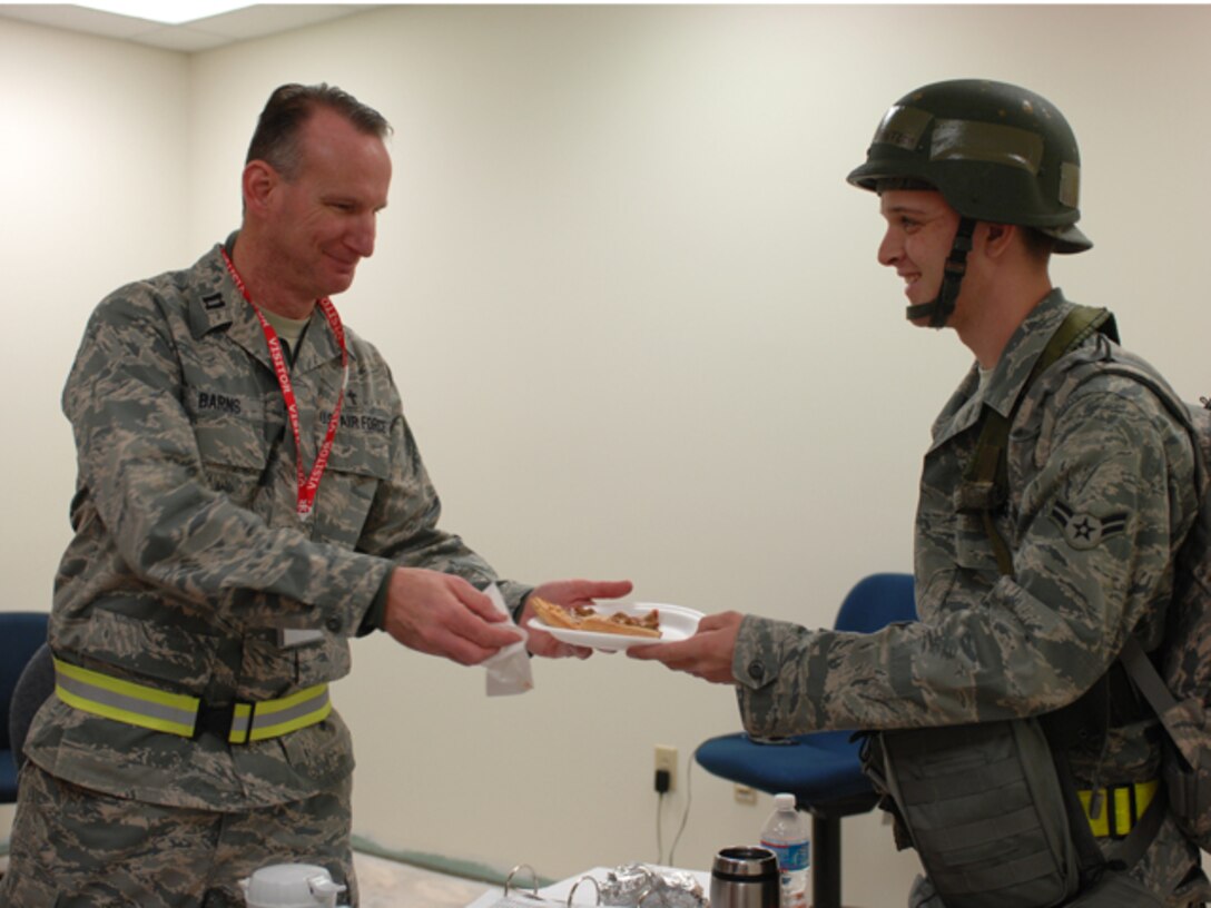 Capt. David Barns, 633d Air Base Wing Chaplain, serves pizza to Airman 1st Class William Stanton, with the 1st Maintenance Squadron, during an Operational Readiness Exercise, at Langley Air Force Base, Va., Feb. 27, 2011. Throughout the processing line chaplains and other agencies hand out snacks and religious material to Airmen  prior to departure to base X. (U.S. Air Force photo by Airman 1st Class Teresa Zimmerman/Released)