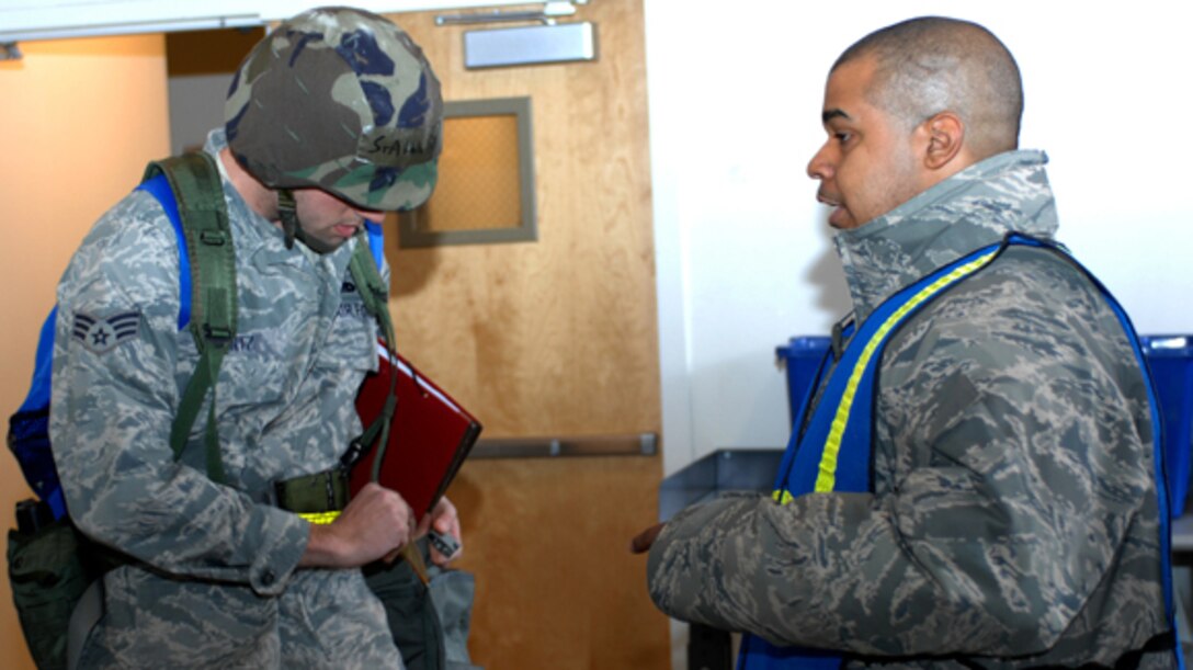 Staff Sgt. Kenneth Brown, 633d Logistics Readiness Squadron mobility bag inspection team, briefs Senior Airman Patrick Wentz, 1st Maintenance Squadron Aerospace Ground Equipment journeyman, during an Operational Readiness Exercise, at Langley Air Force Base, Va., Feb. 27, 2011. Staff Stg. Brown makes sure Airman Wentz have inspection tags for gas masks and proper caps for canteens to ensure safety. (U.S. Air Force photo by Airman 1st Class Teresa Zimmerman/Released)