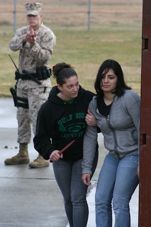 Cpl. Mitchel Mertz, background, draws down on Lance Cpl. Ashley Mizrahi, left, and Lance Cpl. Adrianne M. Rivera as they take part in a suspicious person simulation during exercise Active Shield 2011 here Monday-pow