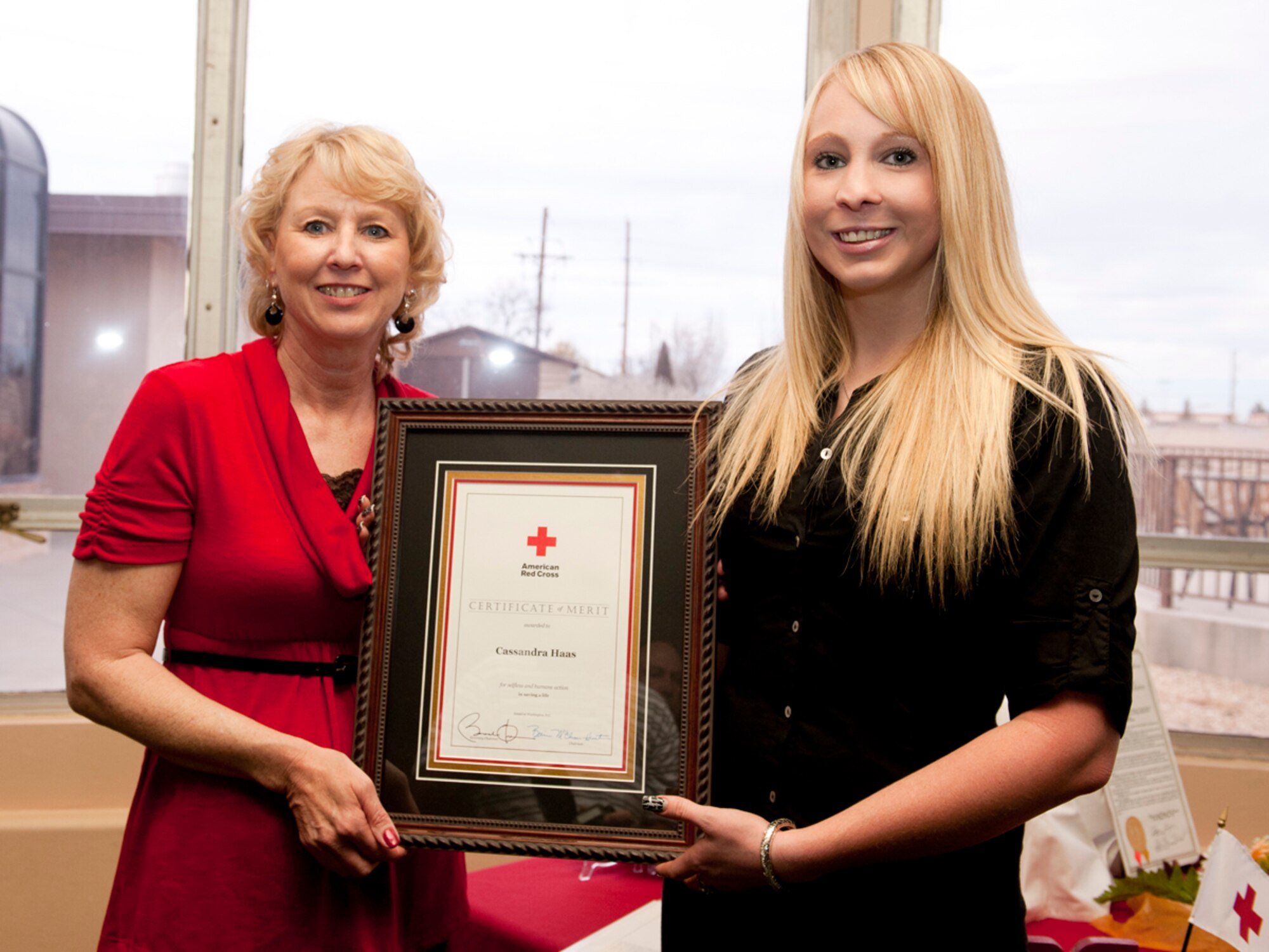HOLLOMAN AIR FORCE BASE, N.M. -- Katherine Peel, American Red Cross instructor and trainer, presents Cassandra Hass, a seasonal employee for the 49th Force Support Squadron, with the Red Cross's highest national honor, the "Certificate of Merit," Feb. 18, 2011, for selfless and humane action in saving a life. Ms. Hass used the skills learned in the American Red Cross Health and Safety Services course to save the life of her grandmother after a snowmobiling accident. (U.S. Air Force photo by Senior Airman Veronica Stamps/ Released)