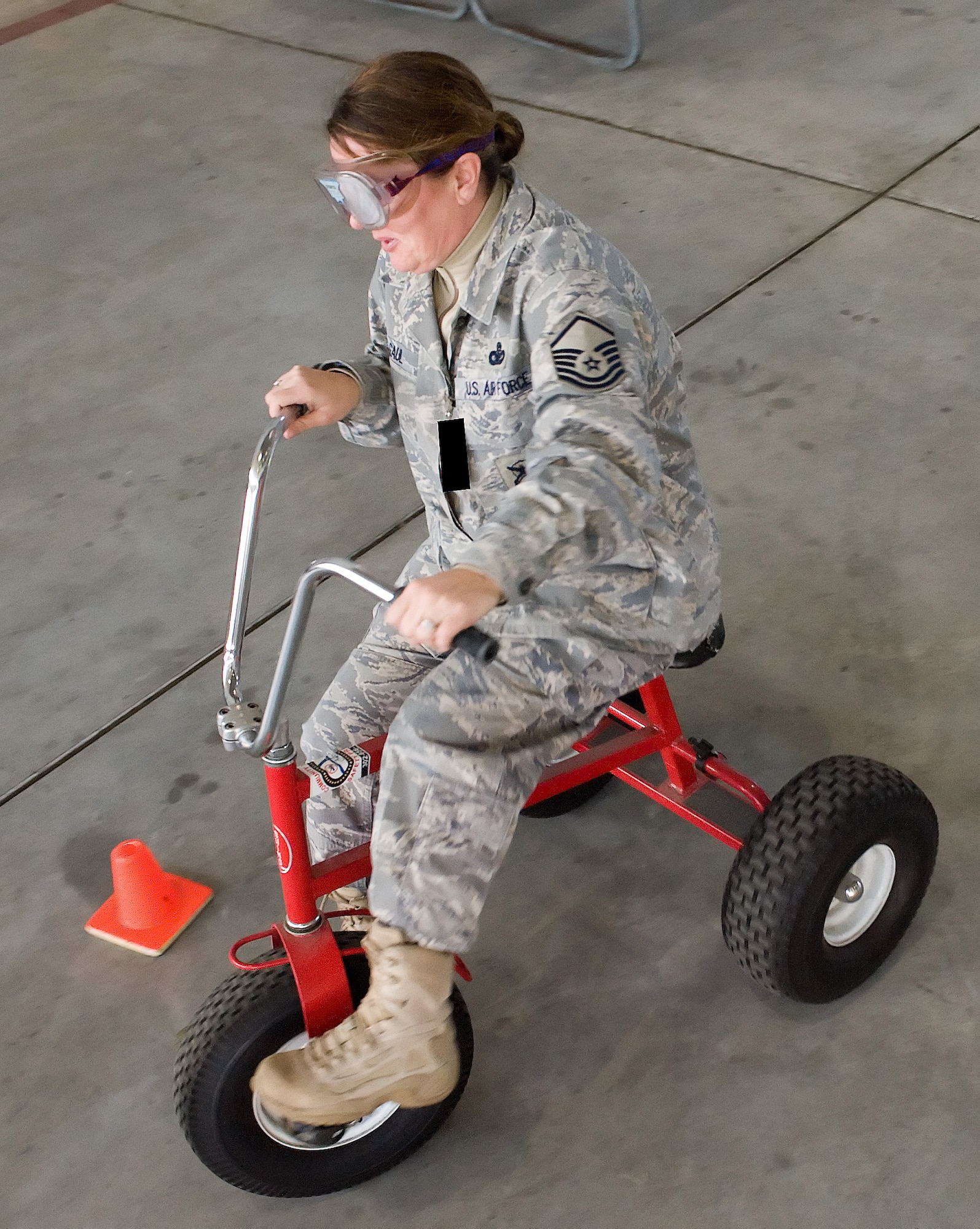 Master Sgt. Michelle Gaul, 436th Security Forces Squadron, rides a tricycle through a snake-like course with goggles that impair her vision Feb. 25, 2011, at Dover AFB, Del. (U.S. Air Force photo/Jason Minto) Photo altered for security purposes.