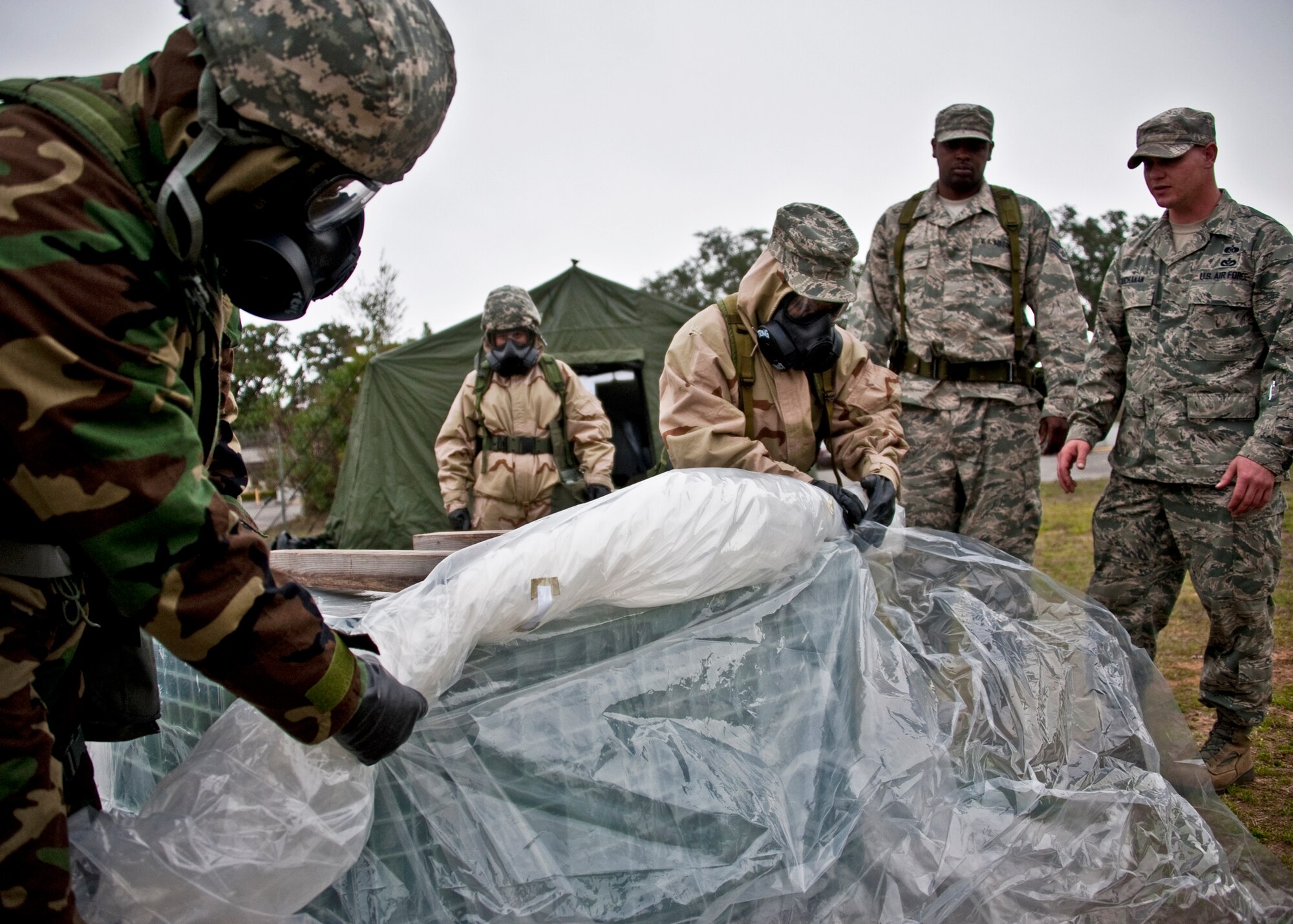 Airmen roll up “contaminated” plastic that was used to protect vital equipment during the Phase II exercise Feb. 24 at Eglin Air Force Base, Fla.  Phase II included self-aid and buddy care, weapons, and chemical, biological, radiological, nuclear and explosive training.  Airmen learned the proper procedures for self-aid and buddy care, field stripping a weapon and also how to wear and work in their chemical gear and gas masks.  Three chalks of Eglin Airmen participated in Phase I and II exercises as part of an Operational Readiness Exercise throughout the week of Feb. 22-25.  (U.S. Air Force photo/Samuel King Jr.)