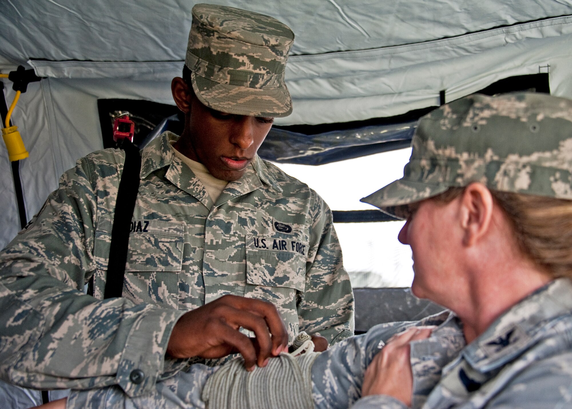 Airman Marcos Diaz, 96th Force Support Squadron, wraps up Col. Carole Farley’s, 96th Inpatient Squadron, arm during Self-Aid and Buddy Care training at the Phase II exercise Feb. 24 at Eglin Air Force Base, Fla.  Phase II included self-aid and buddy care, weapons, and chemical, biological, radiological, nuclear and explosive training.  Airmen learned the proper procedures for cleaning and loading their weapons and also how to wear and work in their chemical gear and gas masks.  Three chalks of Eglin Airmen participated in Phase I and II exercises as part of an Operational Readiness Exercise throughout the week of Feb. 22-25.  (U.S. Air Force photo/Samuel King Jr.)