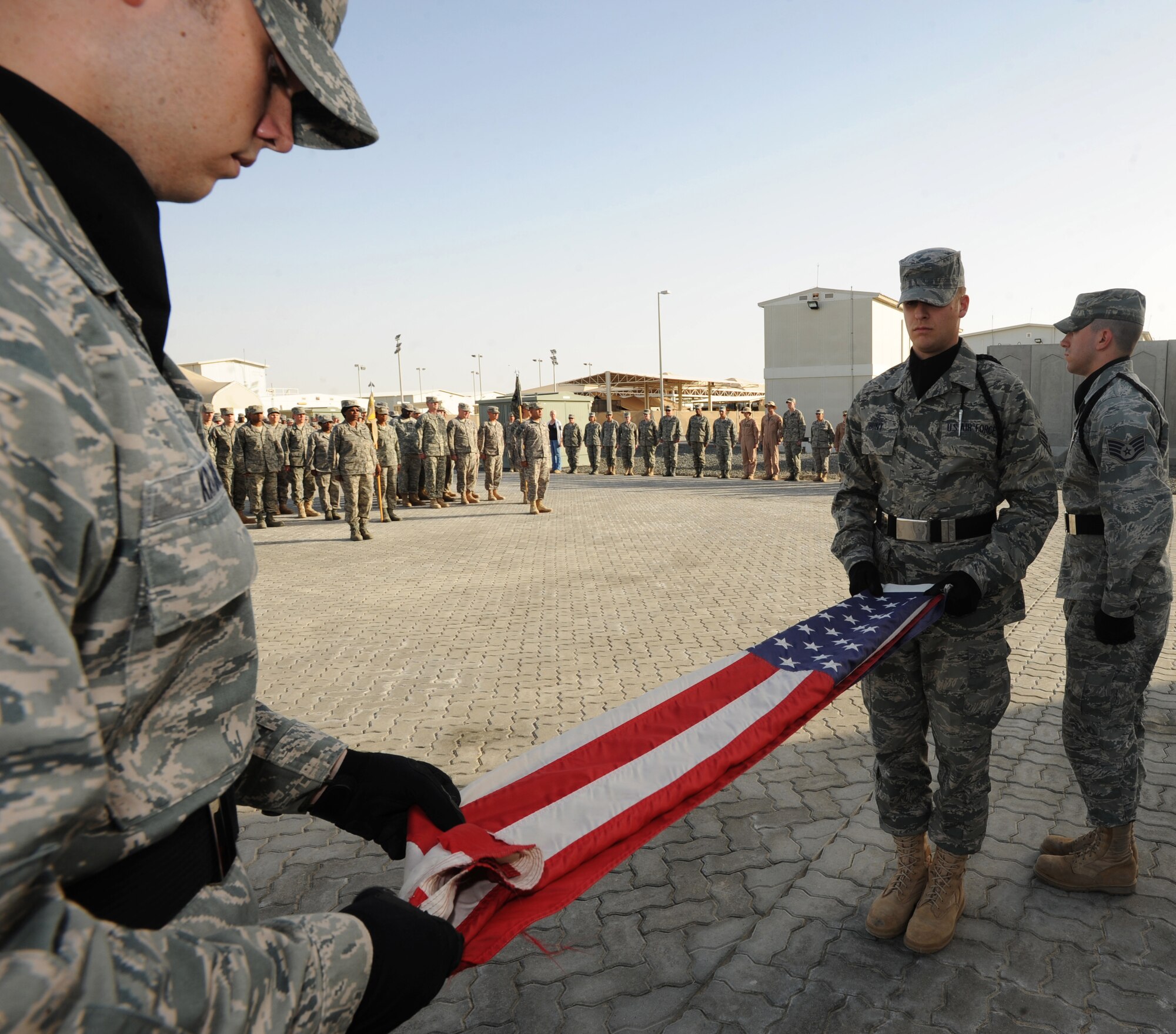 Airman 1st Class Alec Krabbe, 380th Expeditionary Communications Squadron, folds the American Flag while Senior Airman David Hunt, 380th Expeditionary Civil Engineer Squadron, holds it steady Feb. 5, 2011, in Southwest Asia. The retreat ceremony signals the end of the official duty day and serves as a ceremony to pay our respects to the flag. Airman Krabbe is deployed from the 633rd CS, Langley AFB, Virginia; Airman Hunt is deployed from the 27th Special Operations CES, Cannon AFB, New Mexico. (U.S. Air Force photo by Senior Airman Maynelinne De La Cruz)