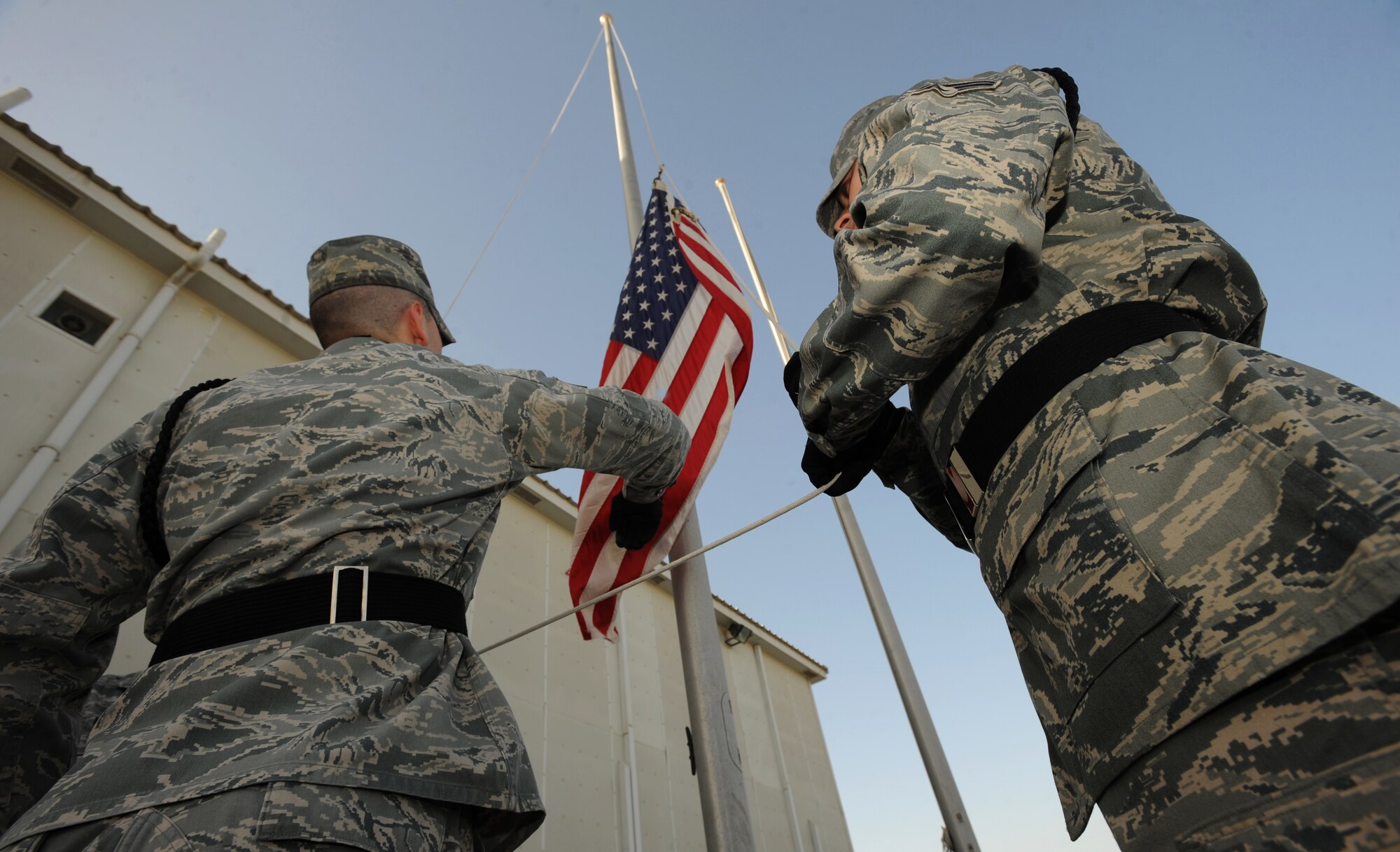 Staff Sgt. Alex Raveling, 380th Expeditionary Force Support Squadron, reaches for the American flag as it flows downward Feb. 5, 2011. The retreat ceremony signals the end of the official duty day and serves as a ceremony to pay our respects to the flag. Sergeant Raveling is deployed from 185 Air Refueling Wing, Air National Guard Base, Iowa. (U.S. Air Force photo by Senior Airman Maynelinne De La Cruz)