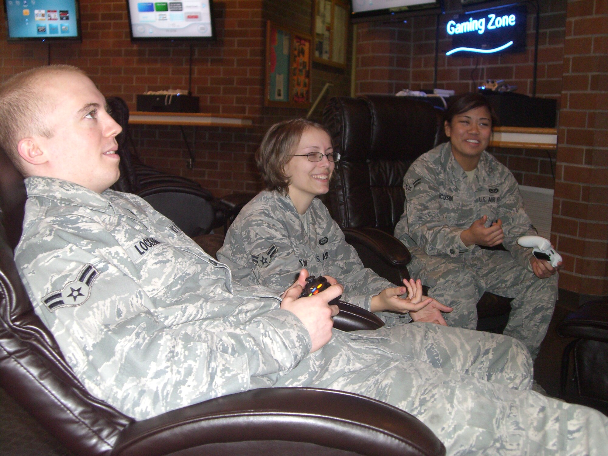 Airman 1st Classes Richard Lockhart, left, 62nd Aircraft Maintenance Squadron, Alicia Johnston, center, 62nd Operations Group, and Staci Ducusin, right, 627th Civil Engineer Squadron, share a laugh while playing video games in the Airman Activities Center Feb. 25 at Joint Base Lewis-McChord, Wash. (U.S. Air Force photo/Tyler Hemstreet) 