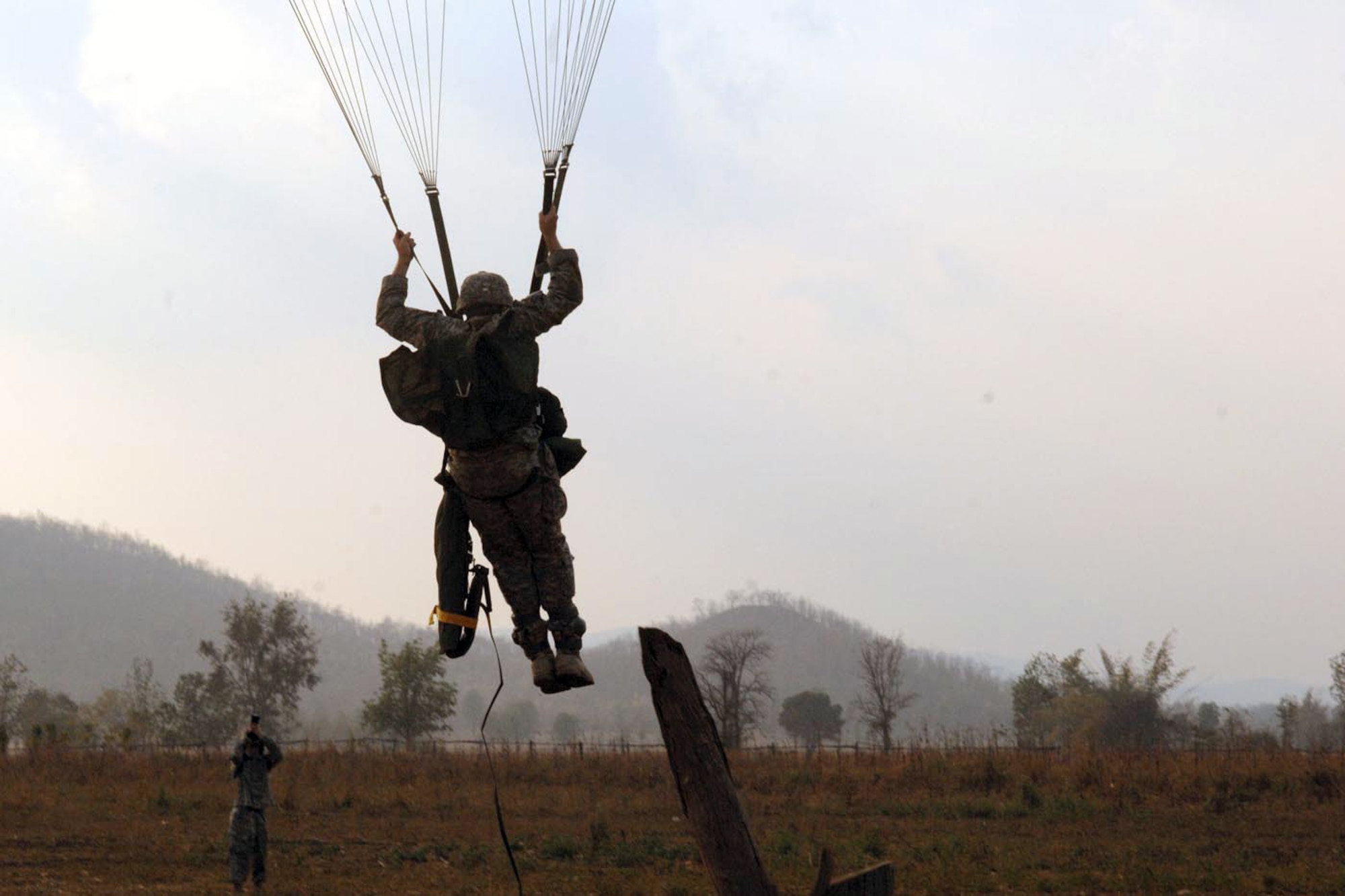 A U.S. paratrooper from 3rd Battalion, 509th Infantry Regiment (Airborne), prepares to land with his combat equipment on Wang Luk East Drop Zone during Exercise Cobra Gold 2011. (U.S. Army photo/Staff Sgt. Matthew E. Winstead)