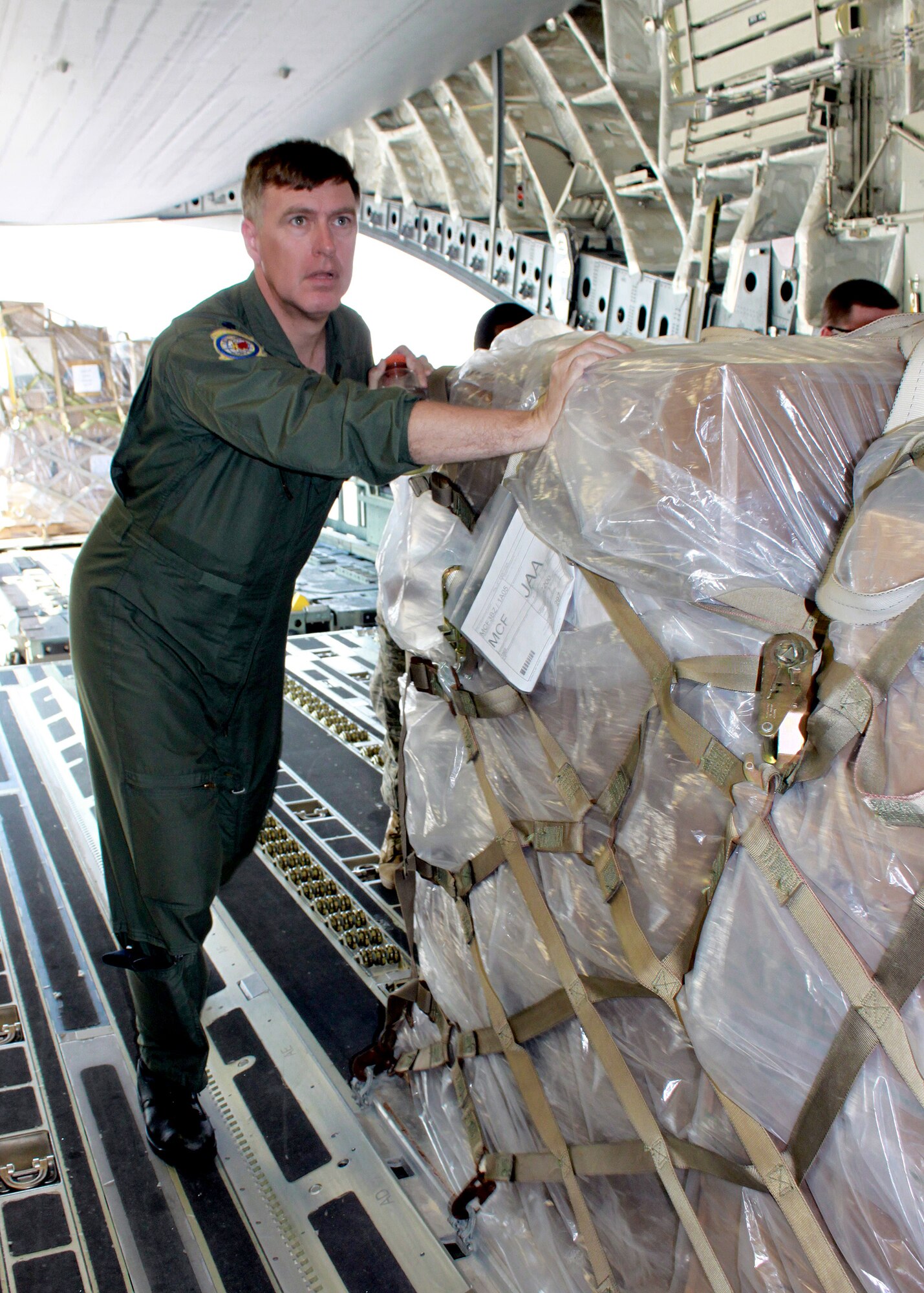 Lt. Col. Peter Debusmann helps the aircrew push cargo palettes into place aboard the C-17 Globemaster III Feb. 18, 2011, at Joint Base McGuire-Dix-Lakehurst, N.J. The C-17 aircrew accomplished training requirements with stops at three bases to upload and download cargo under the Denton Program intended for delivery to Guyana and Afghanistan. The Denton Program authorizes the Department of Defense to transport donated assistance material, free of charge, on a space-available basis and of no cost to the government other than the cost of transportation itself. Colonel Debusmann is a 732nd Airlift Squadron pilot. (Courtesy photo)