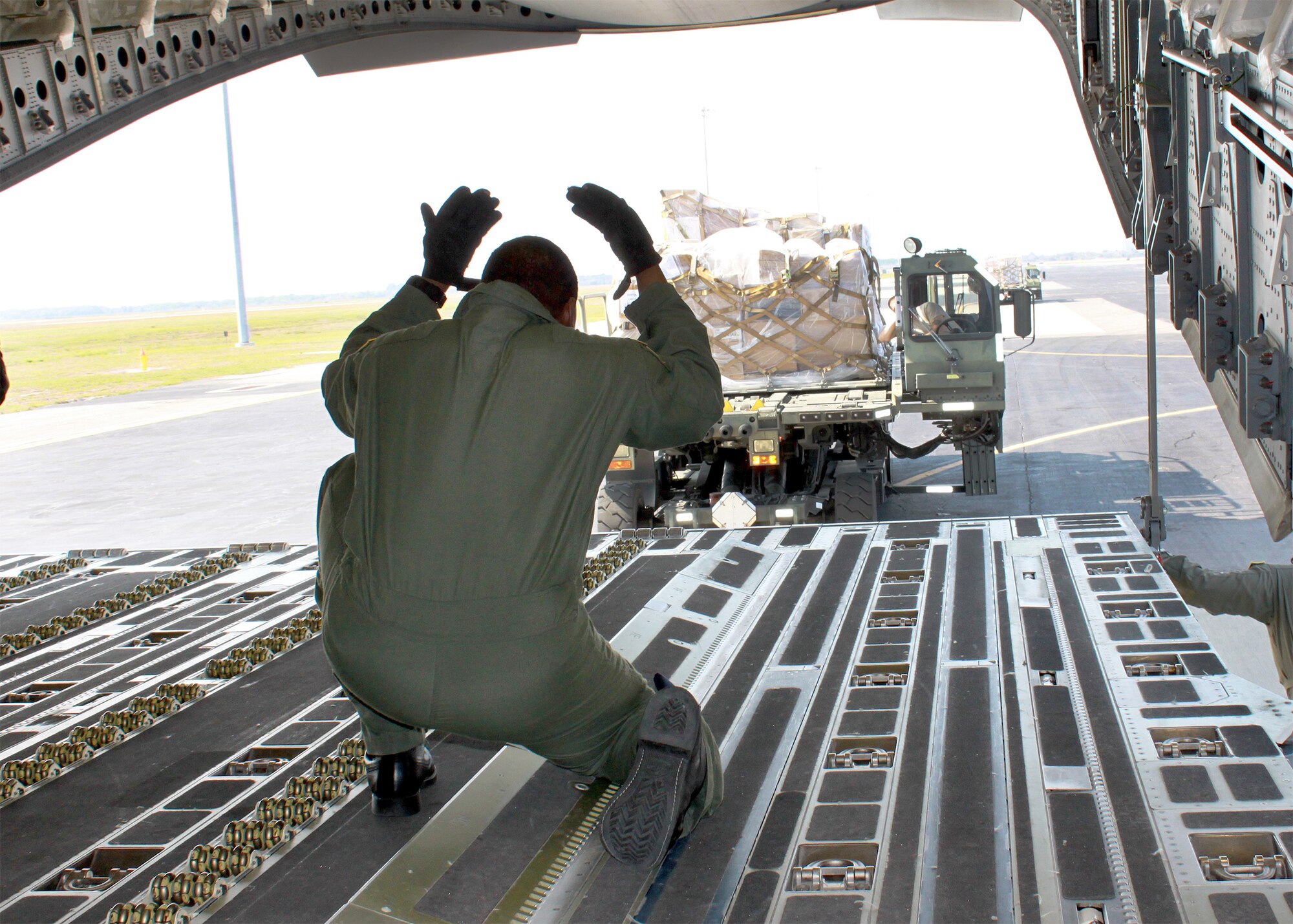 Tech. Sgt. Sean McClendon directs the positioning of cargo before uploading to the C-17 Globemaster III Feb. 18, 2011, at Joint Base McGuire-Dix-Lakehurst, N.J. The C-17 aircrew accomplished training requirements with stops at three bases to upload and download cargo under the Denton Program intended for delivery to Guyana and Afghanistan. The Denton Program authorizes the Department of Defense to transport donated assistance material, free of charge, on a space-available basis and of no cost to the government other than the cost of transportation itself. Sergeant McClendon is a 732nd Airlift Squadron loadmaster. (Courtesy photo)