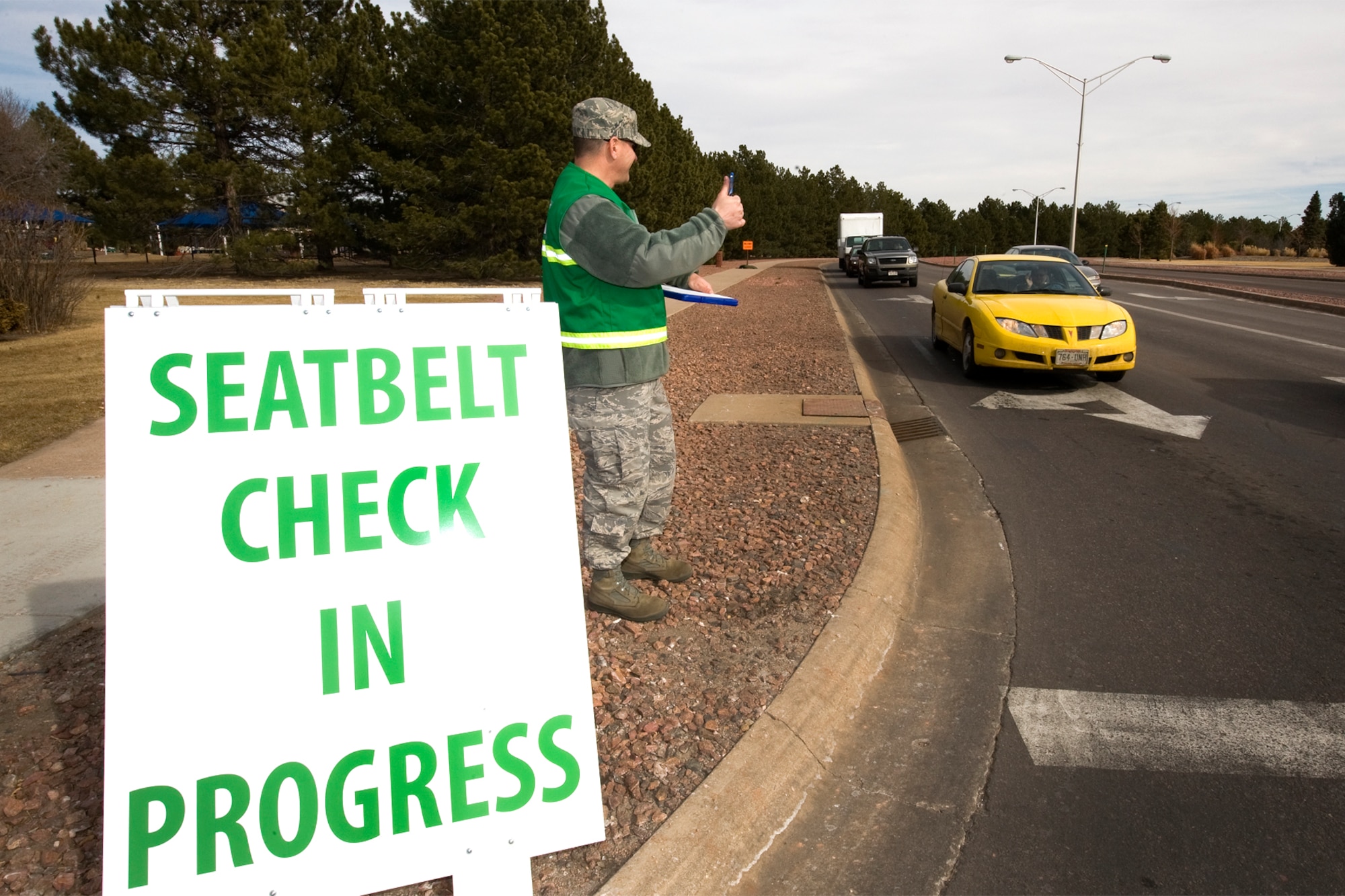 PETERSON AIR FORCE BASE, Colo. -- Chief Master Sgt. Thomas Trottier, 21st Space Wing command chief, gives a thumbs-up to drivers as he performs a seatbelt and cell phone check Feb. 18 on Peterson Air Force Base. More than 670 personnel were observed that afternoon. The chief, and members of the 21st Safety Office, observed seven seatbelt offenders and one driver talking on a cell phone without a hands-free device. Overall, there was 98 percent compliance. The 21st Space Wing continued compliance observations and enforcement in preparation for the up-coming Operational Readiness Inspection and Unit Compliance Inspection, which began Feb. 25. (U.S. Air Force photo/Craig Denton)
