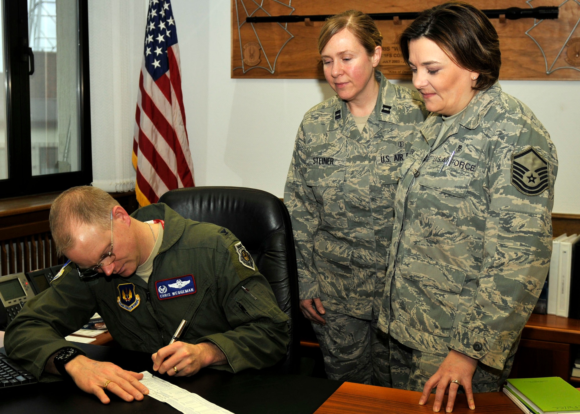 SPANGDAHLEM AIR BASE, Germany- Col. Christopher Weggeman, 52nd Fighter Wing commander, signs Air Force Assistance Fund Campaign form as Master Sgt. Charmagne Bliven, right, 52nd FW assistant project manager, and Capt. Nicole Steiner, 52nd FW installation project manager, watch March 1. The AFAF was established to provide for an annual effort to raise funds for charitable affiliates that provide support to the active-duty members, retirees, reservists, guardsmen, their dependents and surviving spouses in need. The AFAF officially began March 1. (U.S. Air Force photo/Airman 1st Class Brittney Frees)