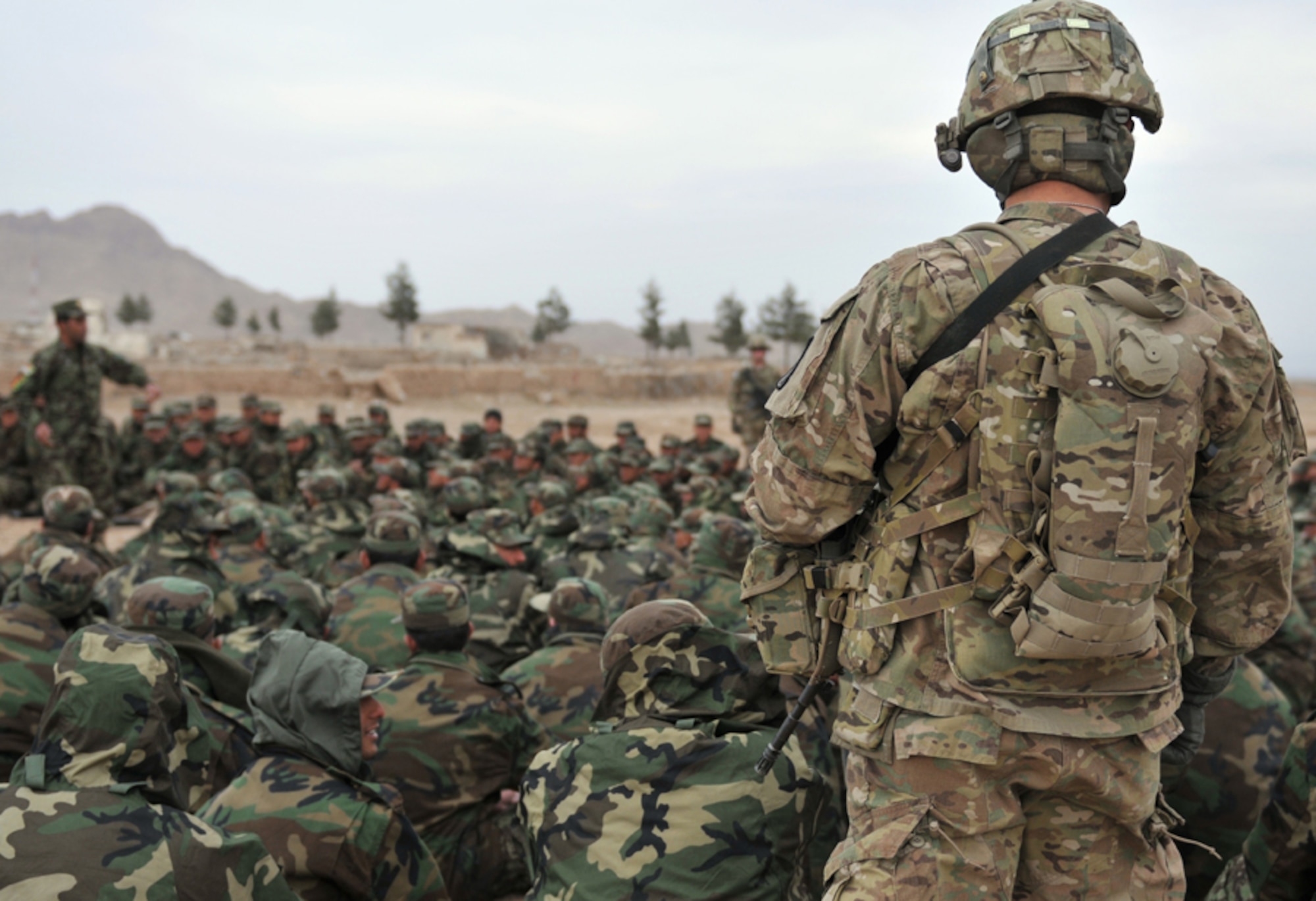 HERAT, Afghanistan -- U.S. Army Spc. Dale Dillahunty, an Afghan National Army basic military training recruit mentor, watches as an ANA soldier issues instructions to recruits during Military Operations in Urban Terrain at an outside-the-wire location near Camp Zafar, Herat Province, Afghanistan, Feb. 20, 2011. The trainees learned to tactfully clear rooms and secure buildings during the training. (U.S. Air Force photo/Tech. Sgt. Kevin Wallace)