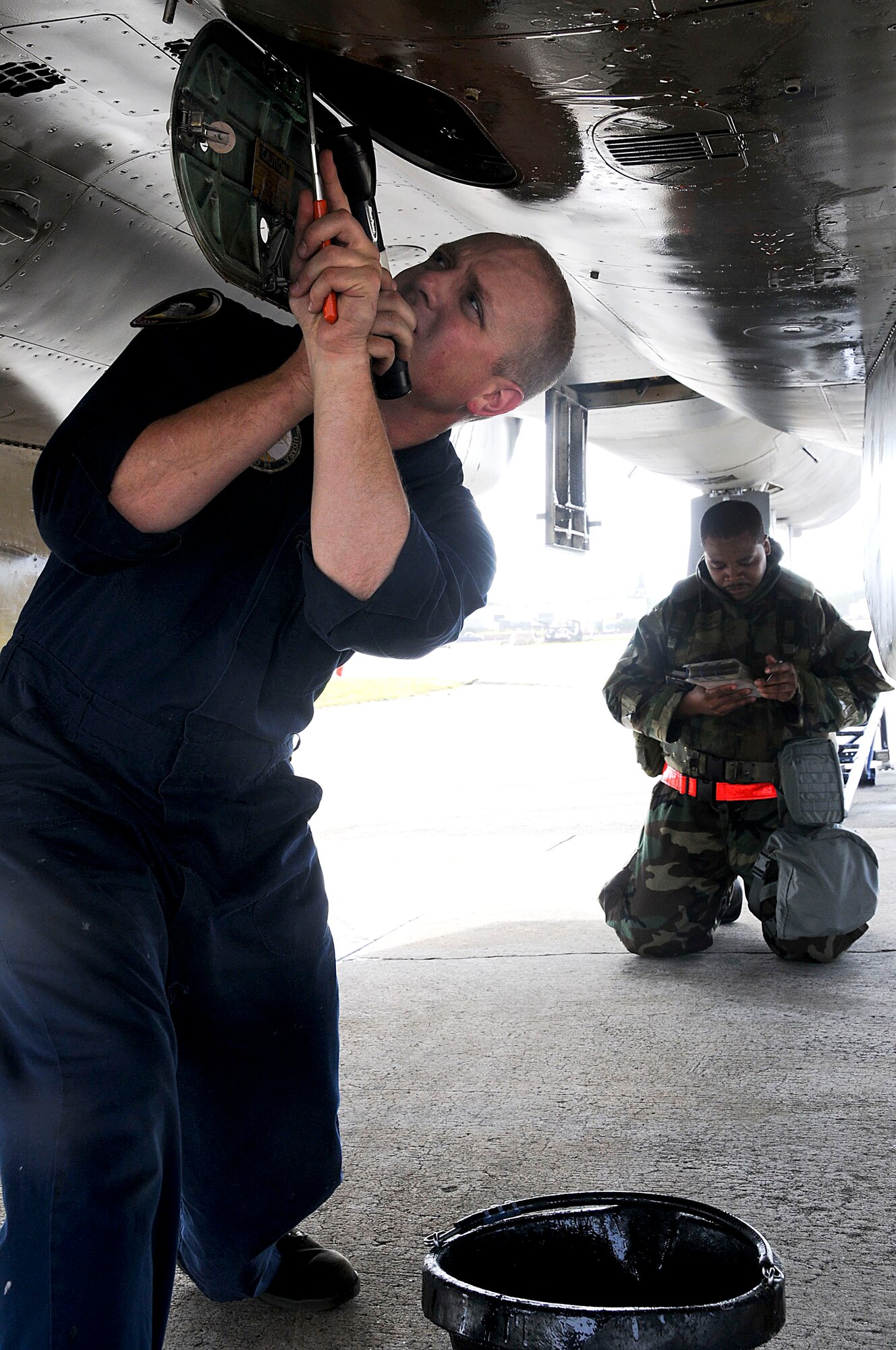 Senior Airman Ryan Cullen, 44th Aircraft Maintenance Unit crew chief, checks the oil quantity levels while Staff Sgt. Alexander Morris, 67th Aircraft Maintenance Unit armament load crew chief, reviews the checklist before downloading missiles during the Beverly High 11-03 exercise at Kadena Air Base, Feb 28. This post-flight inspection ensures that the aircraft is ready for potential flights and all weapons are properly removed from the aircraft.  (U.S. Air Force photo/Staff Sgt. Darnell T. Cannady)