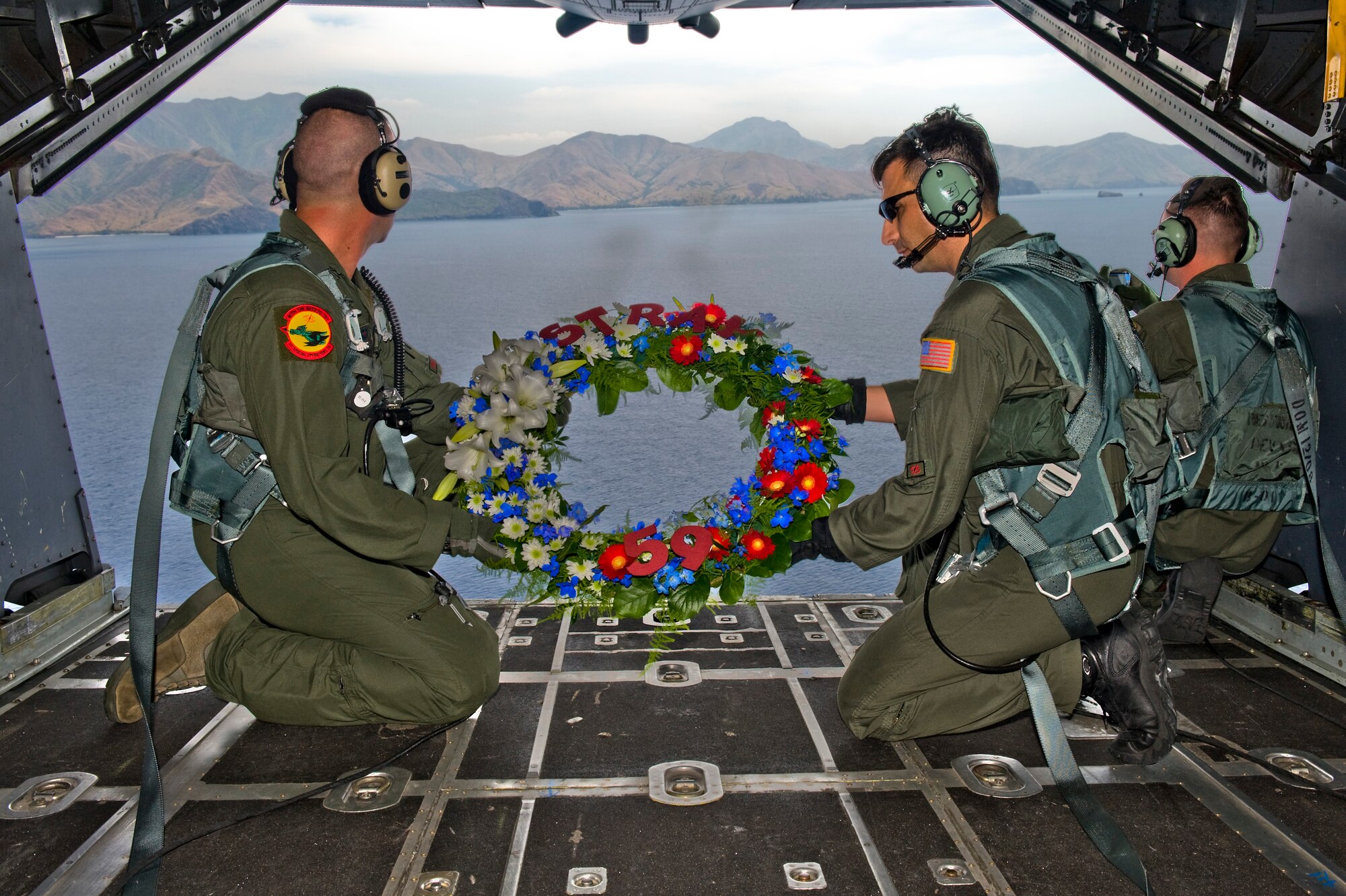 NEAR CAPONES ISLAND, Philippines -- Tech Sgt. Christopher Hughes (left) and Senior Master Sgt. Randy Perreault, both loadmasters with the 1st Special Operations Squadron, prepare to release a wreath in memorial of STRAY 59 while on aboard an MC-130H Combat Talon II Feb. 26. The flight was to honor fallen brethren that were lost 30 years ago when a 1st SOS MC-130E, call sign STRAY 59, crashed during an exercise killing eight crew members and 15 passengers. (U.S. Air Force photo by Staff Sgt. Jonathan Steffen)