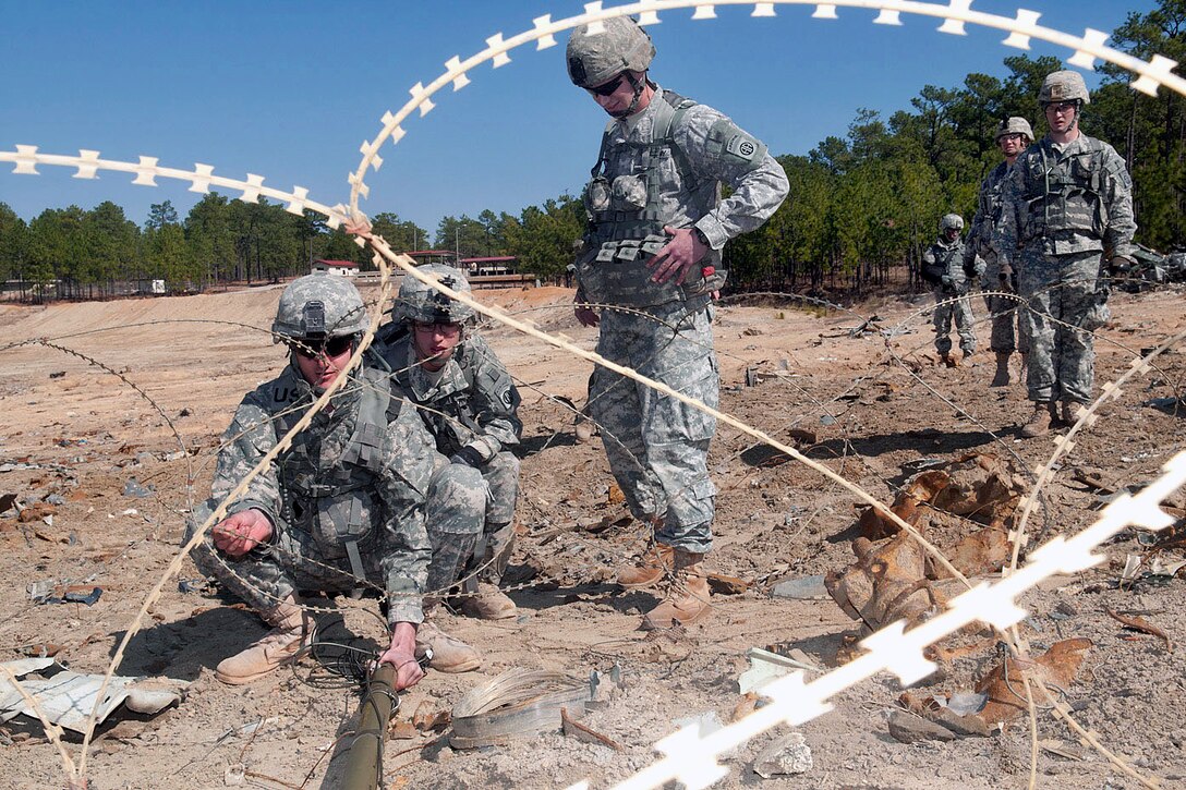 Army Spc. Joshua Hutchins and Spc. Ryan Frye thread a Bangalore torpedo through a barrier of barbed wire during combat engineer training on Fort Bragg, N.C., Feb. 23, 2011. The explosive device is used to clear a path through barbed wire and mines. Hutchins and Frye are assigned to the 82nd Airborne Division’s 1st Brigade Combat Team.