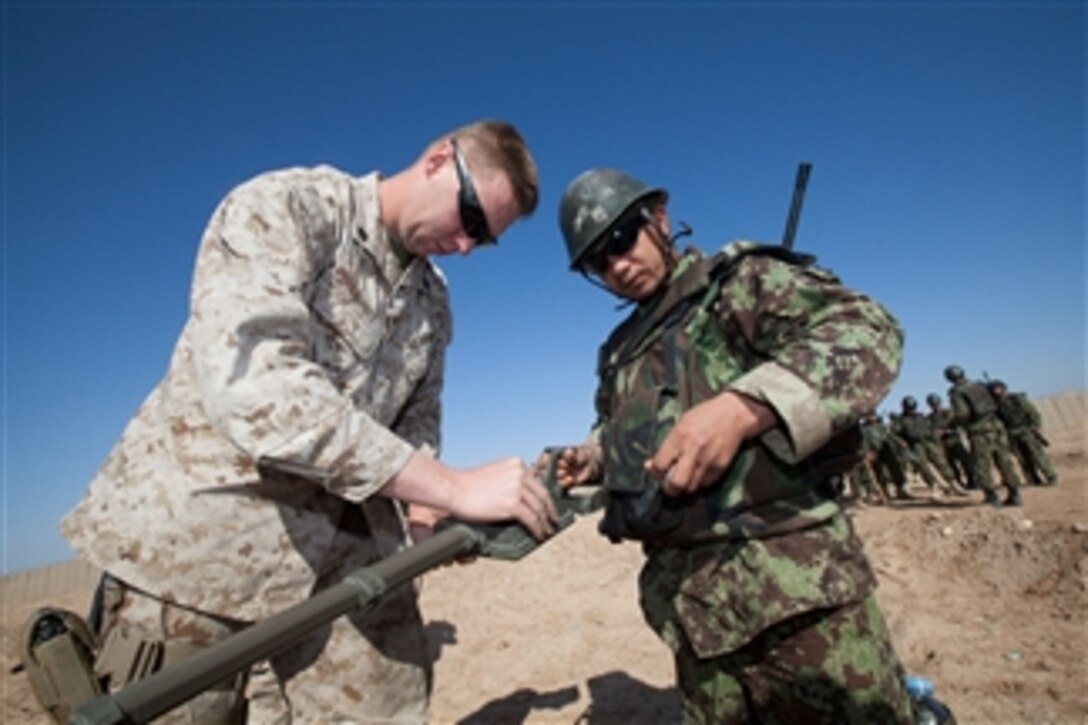 Sgt. Michael Mondt, the lead instructor with the Regimental Combat Team 1 Embedded Training Team, helps an Afghan National Army soldier, with Route Clearance Company, 1st Brigade, 215th Corps, adjust a combat metal detector for the improvised explosive device course at Camp Dwyer, Helmand province, Afghanistan, on Feb. 23, 2011.  
