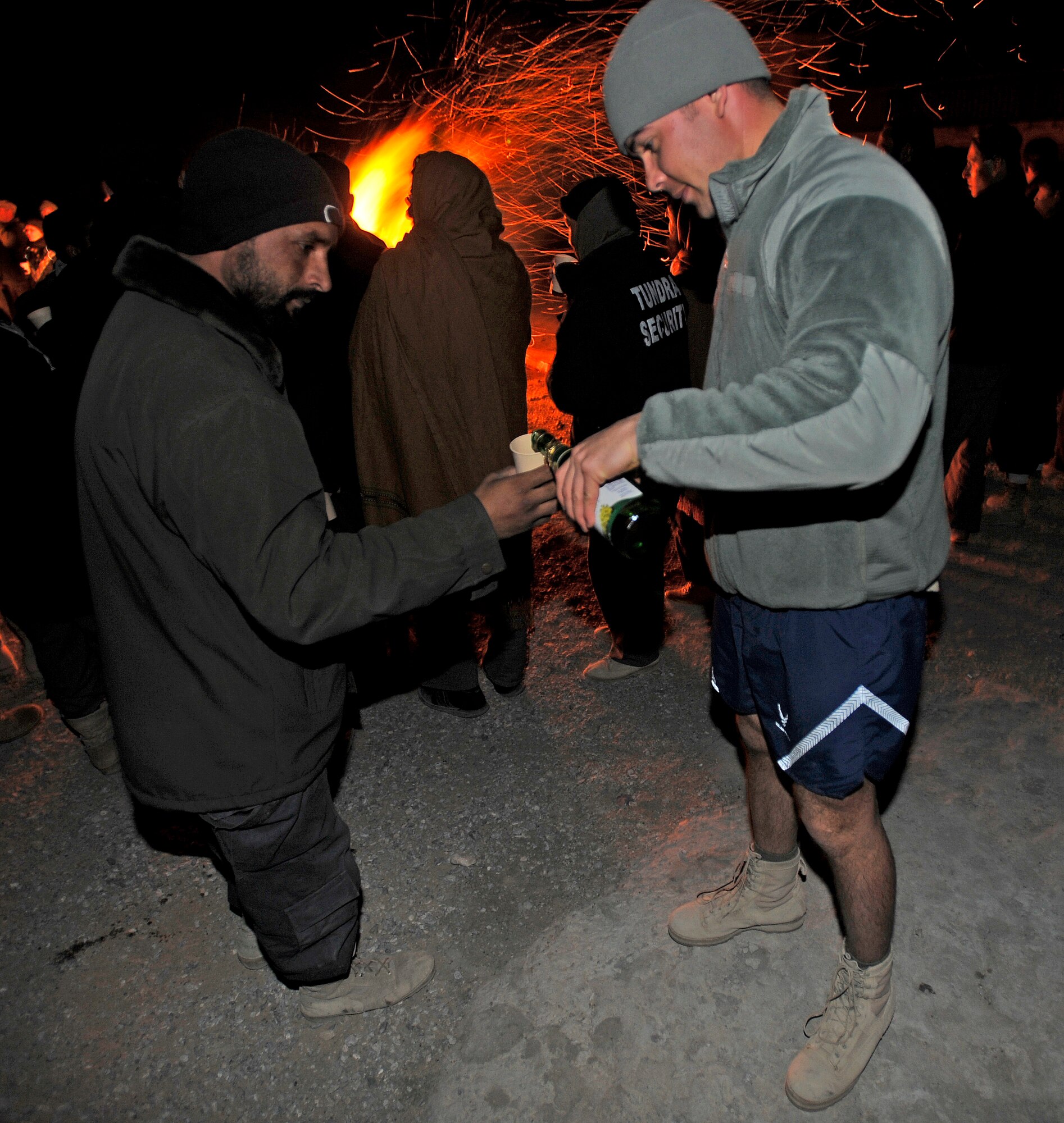 Capt. Edward Ciccarelli pours some sparkling grape juice for one of the Afghan security guards next to a bonfire on New Year's Eve at Forward Operating Base Smart, Afghanistan. Capt. Ciccarelli is assigned to Provincial Reconstruction Team Zabul.  (U.S. Air Force photo/Staff Sgt. Brian Ferguson)