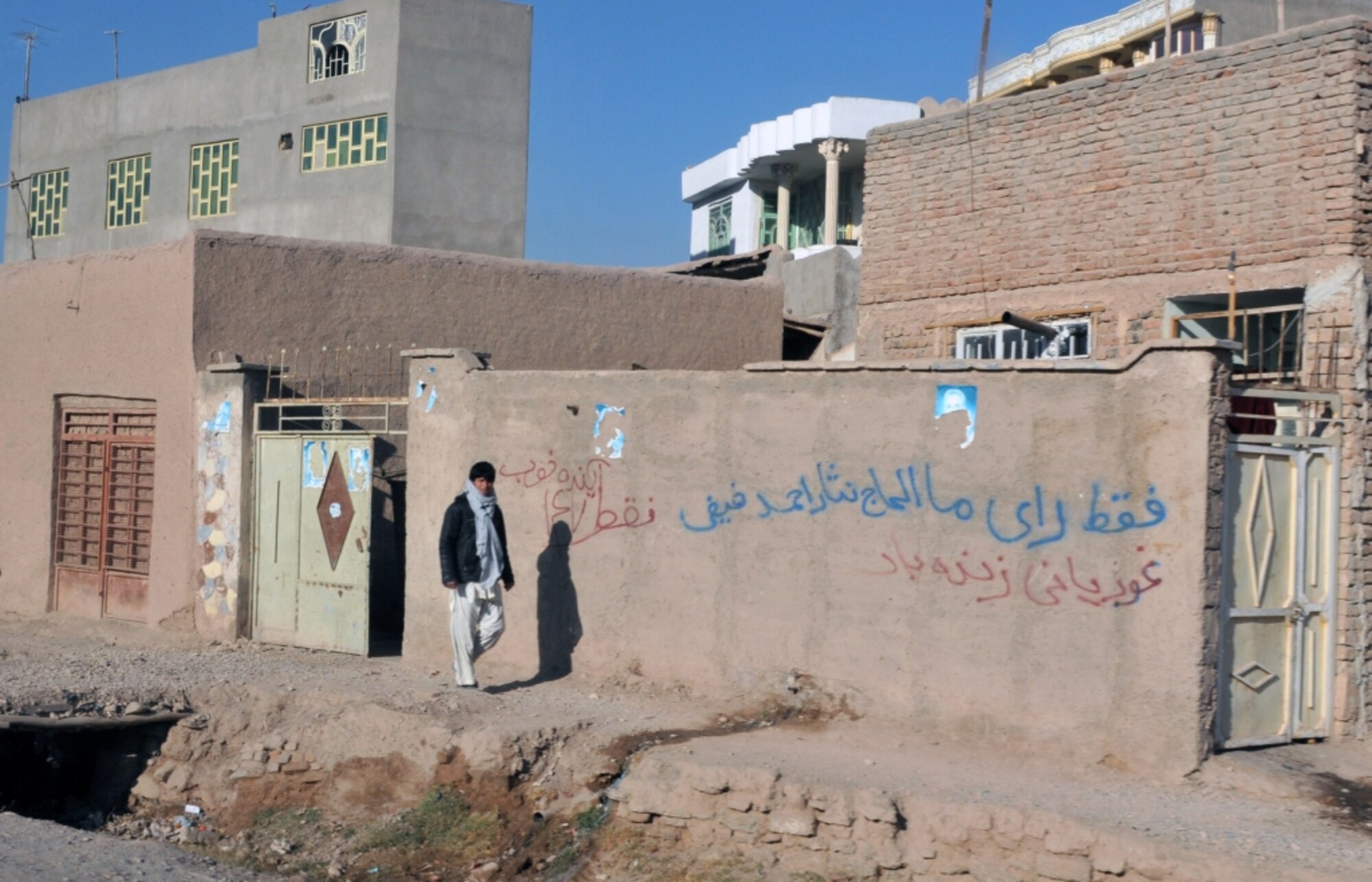An Afghan man walks down a Herat City street Dec. 31, 2010. In addition to older structures as seen in the foreground, relatively new homes and businesses are also being built (background) in Herat City, which is increasingly becoming a benchmark for progress in Afghanistan. (U.S. Air Force photo/Tech. Sgt. Kevin Wallace)