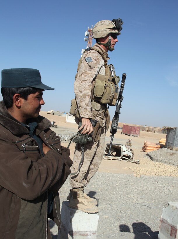 Major Michael Mullins, logistics officer for Task Force Nimruz, Regimental Combat Team 2, and an Afghan police officer scan for an improvised explosive device on the highway running through Delaram, Jan. 3. Shop owners reported the roadside bomb to Afghan police. Marines helped clear the area until explosive ordnance disposal Marines safely removed and destroyed the IED.