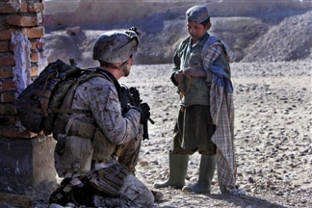 U.S. Marine Corps Cpl. Patrick Kelley speaks with an Afghan boy while providing security during an inspection of a new school being built in Ghartallah, Musa Qal’eh district, Afghanistan, on Dec. 24, 2010.  Kelley, a civil affairs noncommissioned officer, is assigned to the 1st Battalion, 8th Marines.  