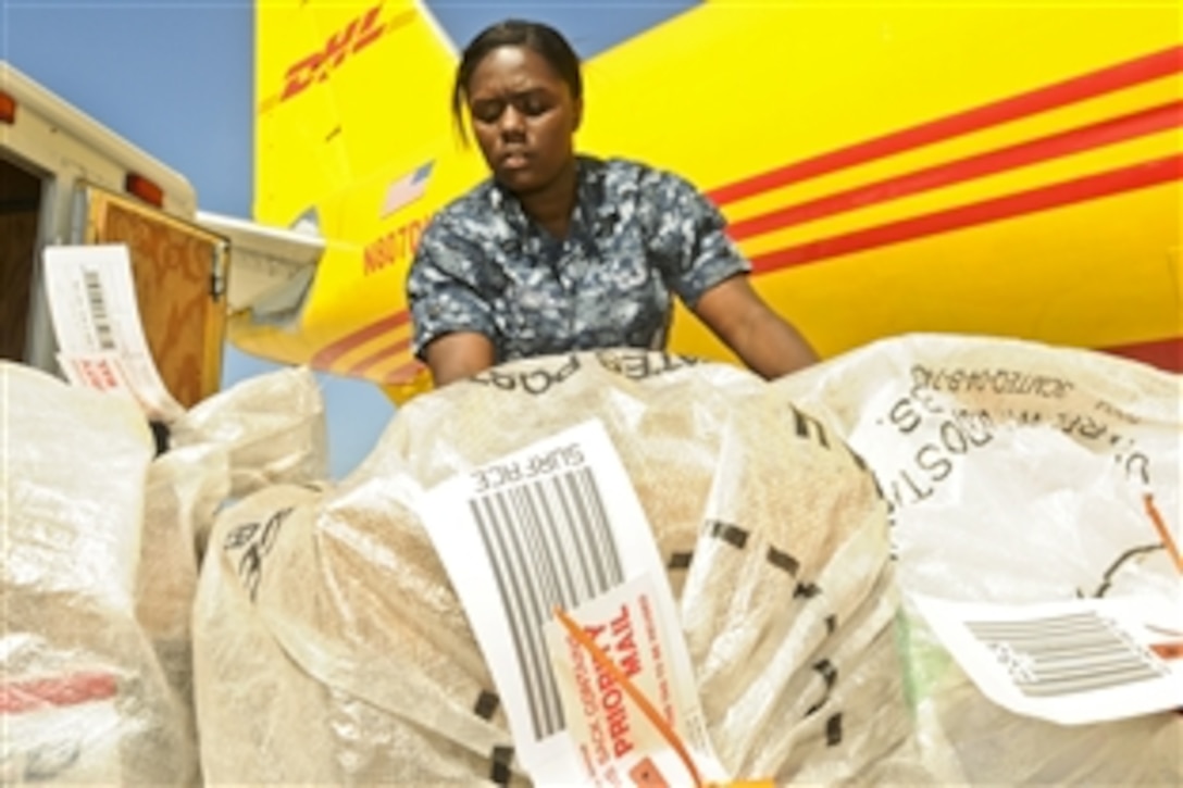 U.S. Navy Seaman Dominique A. Williams sorts Joint Task Force Guantanamo mail after crews unload it from a cargo plane at Leeward Airfield in Guantanamo Bay, Cuba, Dec. 28, 2010. The Joint Task Force Guantanamo postal personnel handle more than 10,000 pounds of mail per week, supporting the Joint Task Force Guantanamo mission. Williams is a logistics specialist.