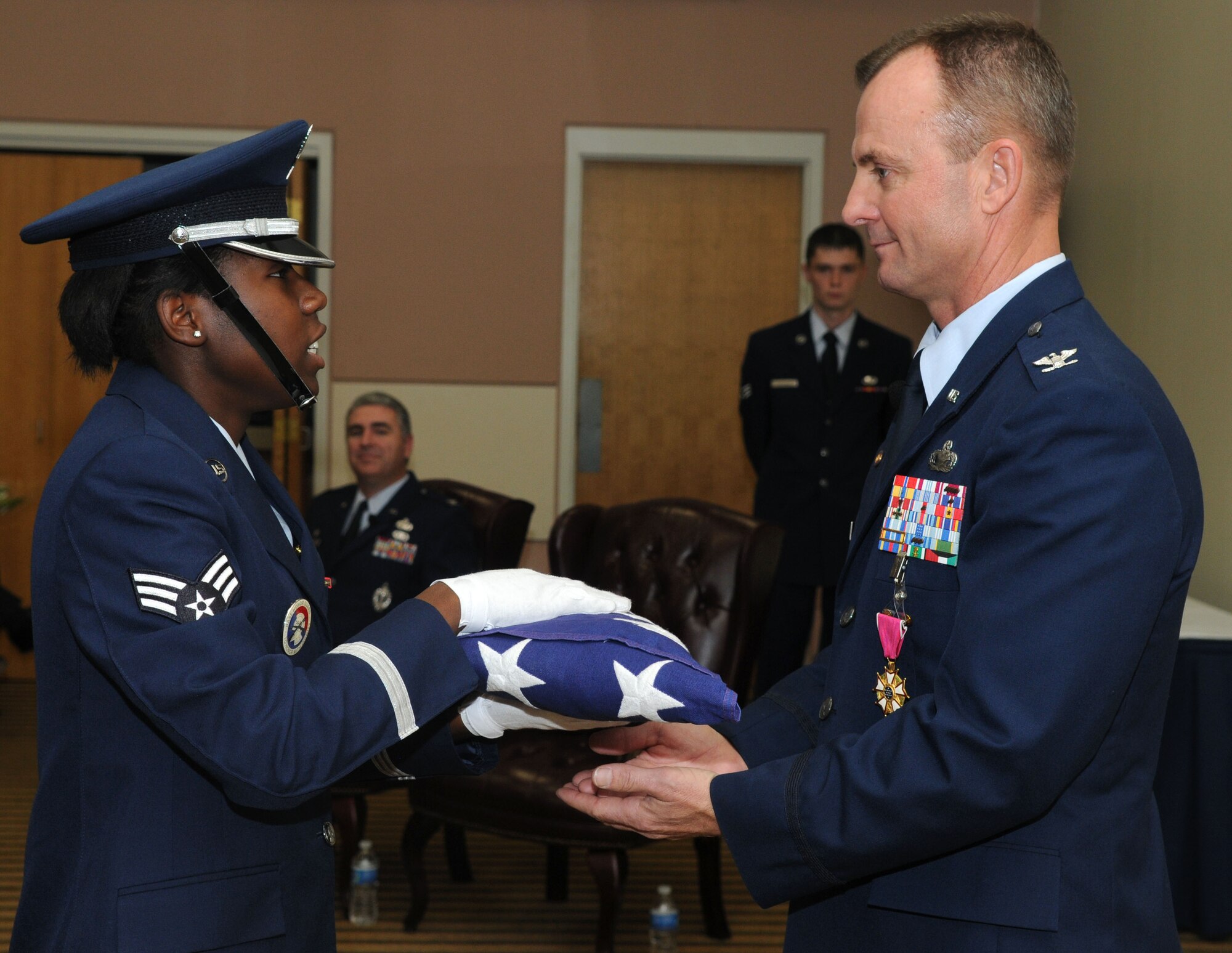 GOODFELLOW AIR FORCE BASE, Texas-- Col. Guy Parker, 17th Mission Support Group Commander, receives the flag from Senior Airman Erica Givens, 17th Communications Squadron, during his retirement ceremony Dec. 20 at the Event Center here.  Col. Parker served the last two years of his career here. (U.S. Air Force photo/ Master Sgt. Randy Mallard) 