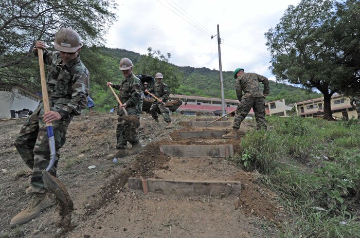 U.S. Sailors assigned to Naval Mobile Construction Battalion 28 Detail Bravo and a Marine assigned to 2nd Marine Logistics Group shovel dirt while laying the foundation for a stair case at Escuela Eloy Alfaro School in Manta, Ecuador, Jan. 5, 2011. Sailors, U.S. Marines and Ecuadorian naval infantry partnered at the school for a week-long subject matter expert exchange in support of Southern Partnership Station 2011, an annual deployment of U.S. ships to the U.S. Southern Command's area of responsibility in the Caribbean and Latin America that involved information sharing with navies, coast guards and civilian services throughout the region.