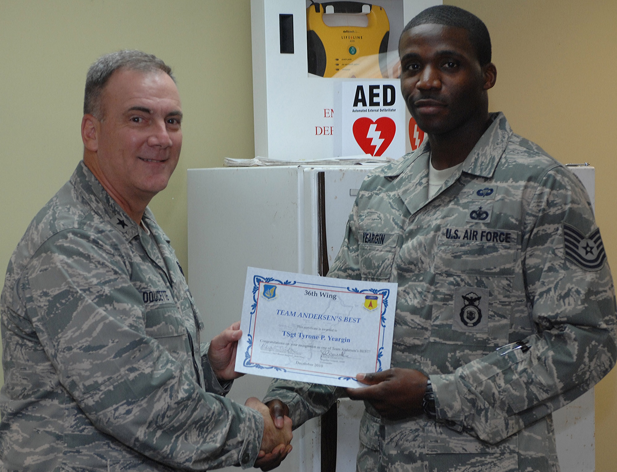 Brig. Gen John Doucette, 36th Wing commander presents Tech. Sgt.  Tyrone Yeargin, 736th Security Forces Operations Noncommissioned officer in charge with an Andersen’s Best certificate Dec. 29 here. This is the second time General Doucette surprised Sergeant Yeargin recently. The Wing commander promoted the new tech. sergeant from staff sergeant after he was selected by leadership for early promotion under the Stripes for Exceptional Performer’s program Dec. 6. (U.S. Air Force photo/Staff. Sgt. Jamie Powell)