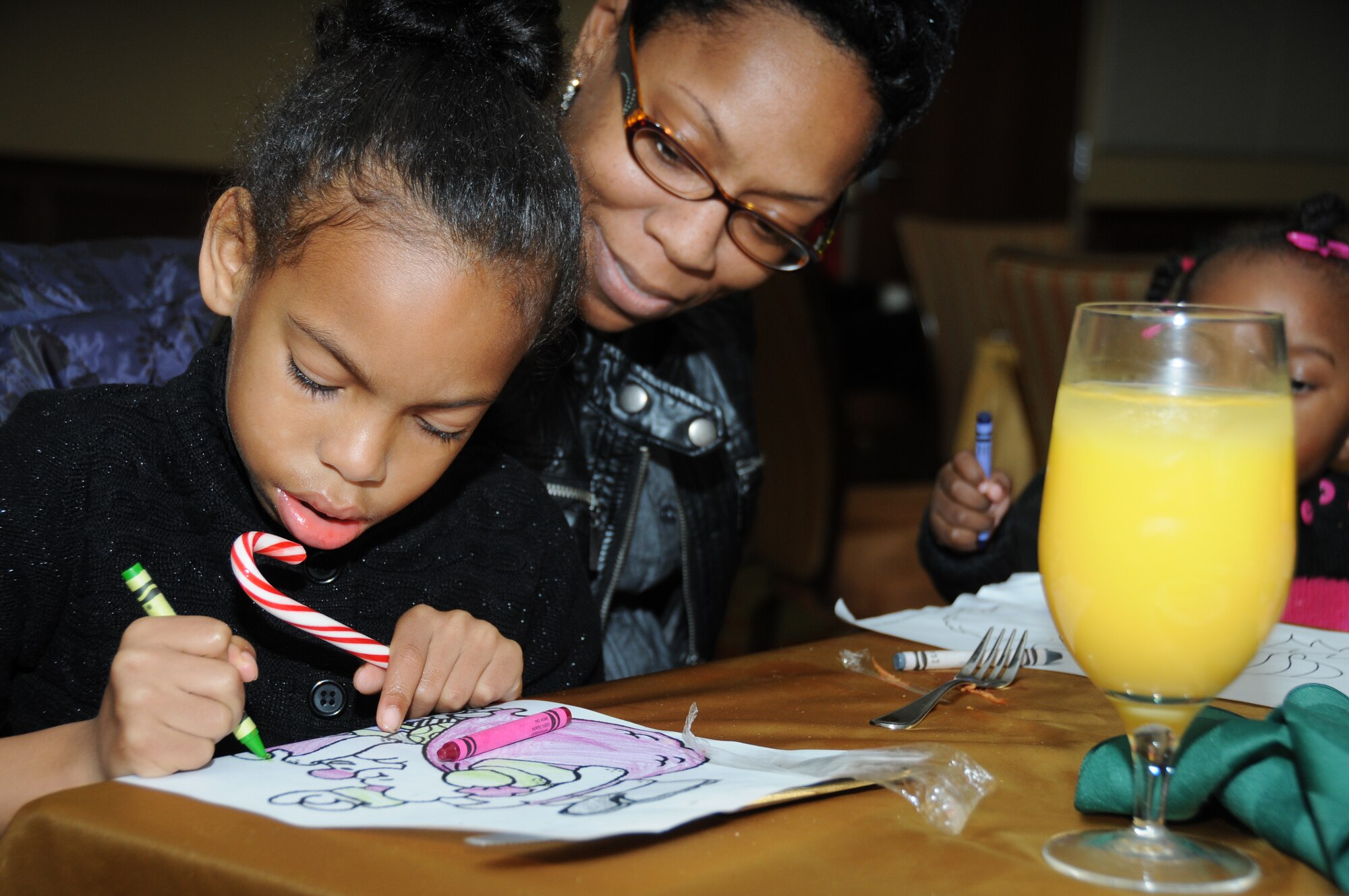Staff Sgt. Serena Ellis, 335th Training Squadron, watches her 6-year-old daughter, Zoe Cardenas, color a Christmas picture during the holiday brunch at the Bay Breeze
Event Center.  (U.S. Air Force photo by Kemberly Groue)