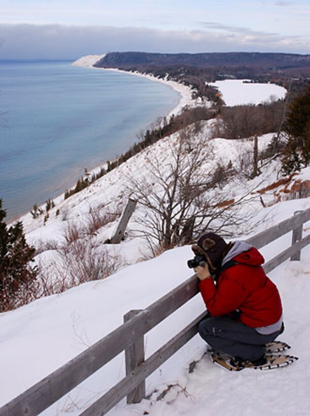 A snowshoer snaps a photo of Lake Michigan from the Empire Bluffs at Sleeping Bear Dunes National Lakeshore west of Traverse City, Mich.  National Park Service officials are waiving admission fees on 17 selected dates throughout 2011 and are encouraging all Americans to make a New Year’s resolution to visit a national park this year.  (National Park Service photo)