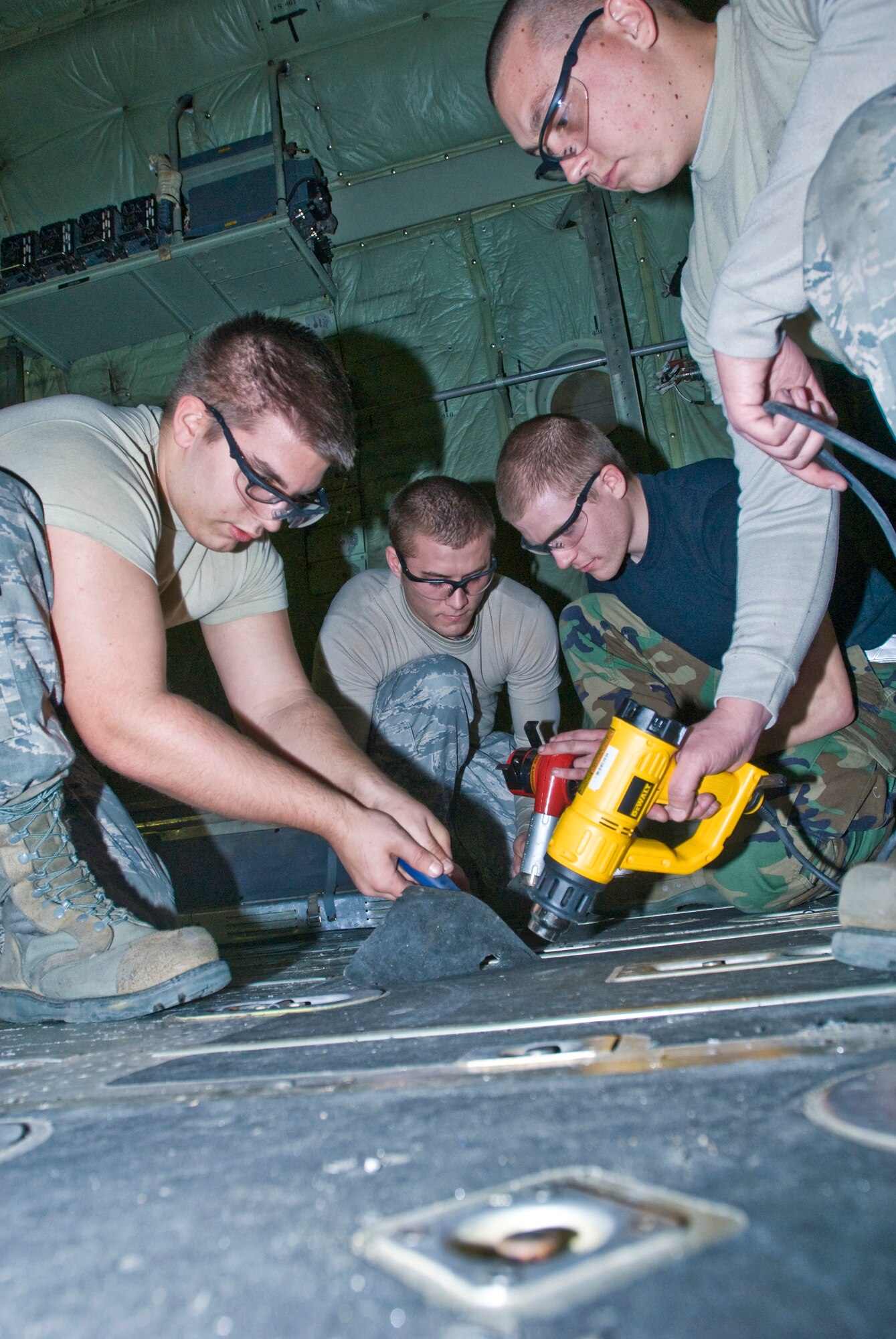 (From left to right)Airman 1st Class David Lee, Senior Airmen Eric McGarrh and Jason Heathington, and Airman 1st Class Evan Owens, all 19th Equipment Maintenance Squadron members, work together to remove anti-skid from a C-130 aircraft’s cargo floors Tuesday. The Air Force saves thousands of dollars by sending aircraft to be refurbished rather than sending them to depot. (U.S. Air Force photo by Staff Sgt. Nestor Cruz)