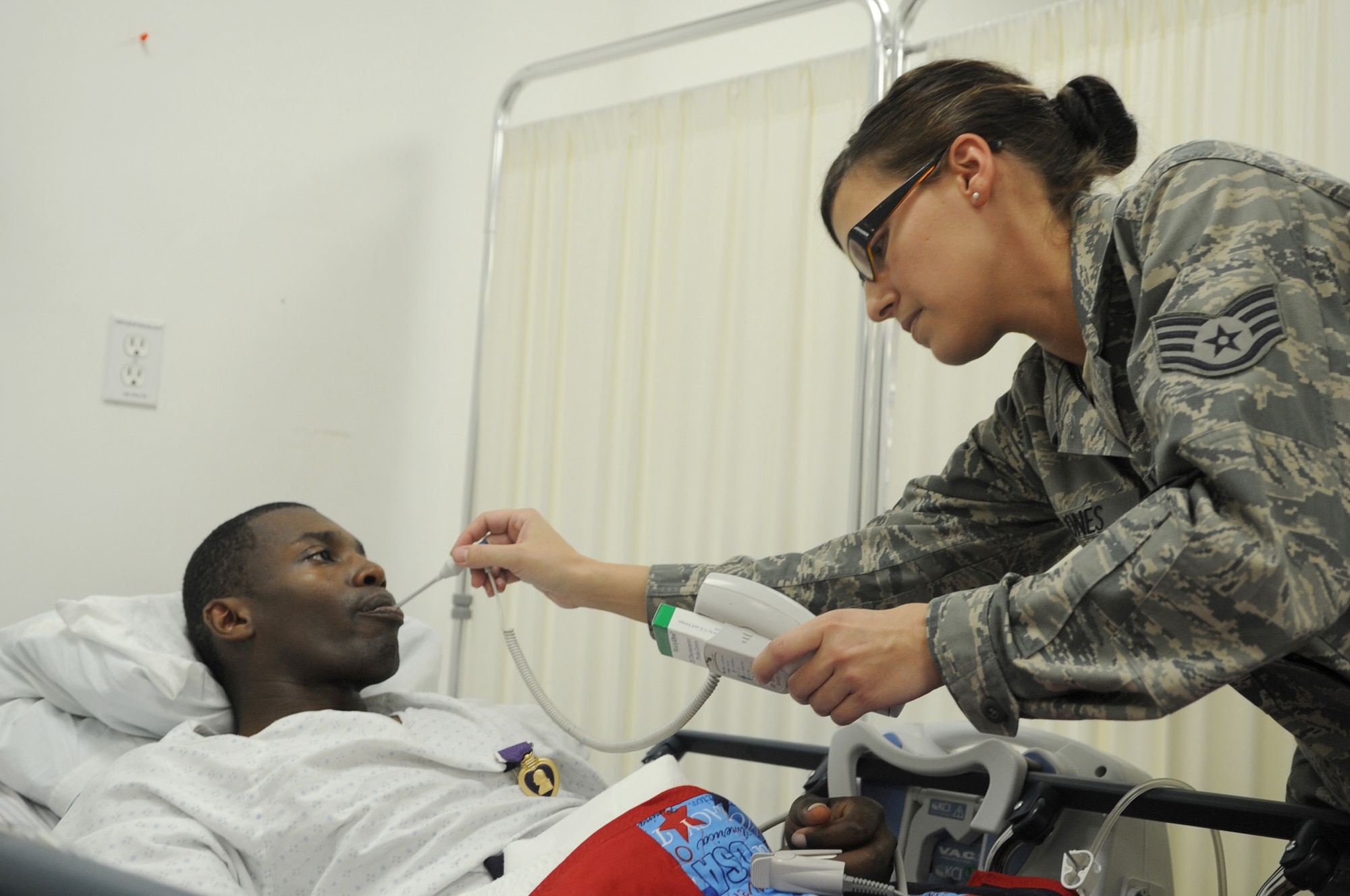 Staff Sgt. April Jones checks Army 1st Lt. Corey Bunch's temperature moments after he received a Purple Heart Jan. 4, 2011, at Joint Base Balad, Iraq. The Charlie Company 1-21 Infantry Battalion member was admitted to the intensive care unit here after her was injured in an improvised explosive device attack near Abu Sayada, Iraq. Sergeant Jones is a 332nd Expeditionary Medical Operations Squadron medical technician. (U.S. Air Force photo/Staff Sgt. Keyonna Fennell)