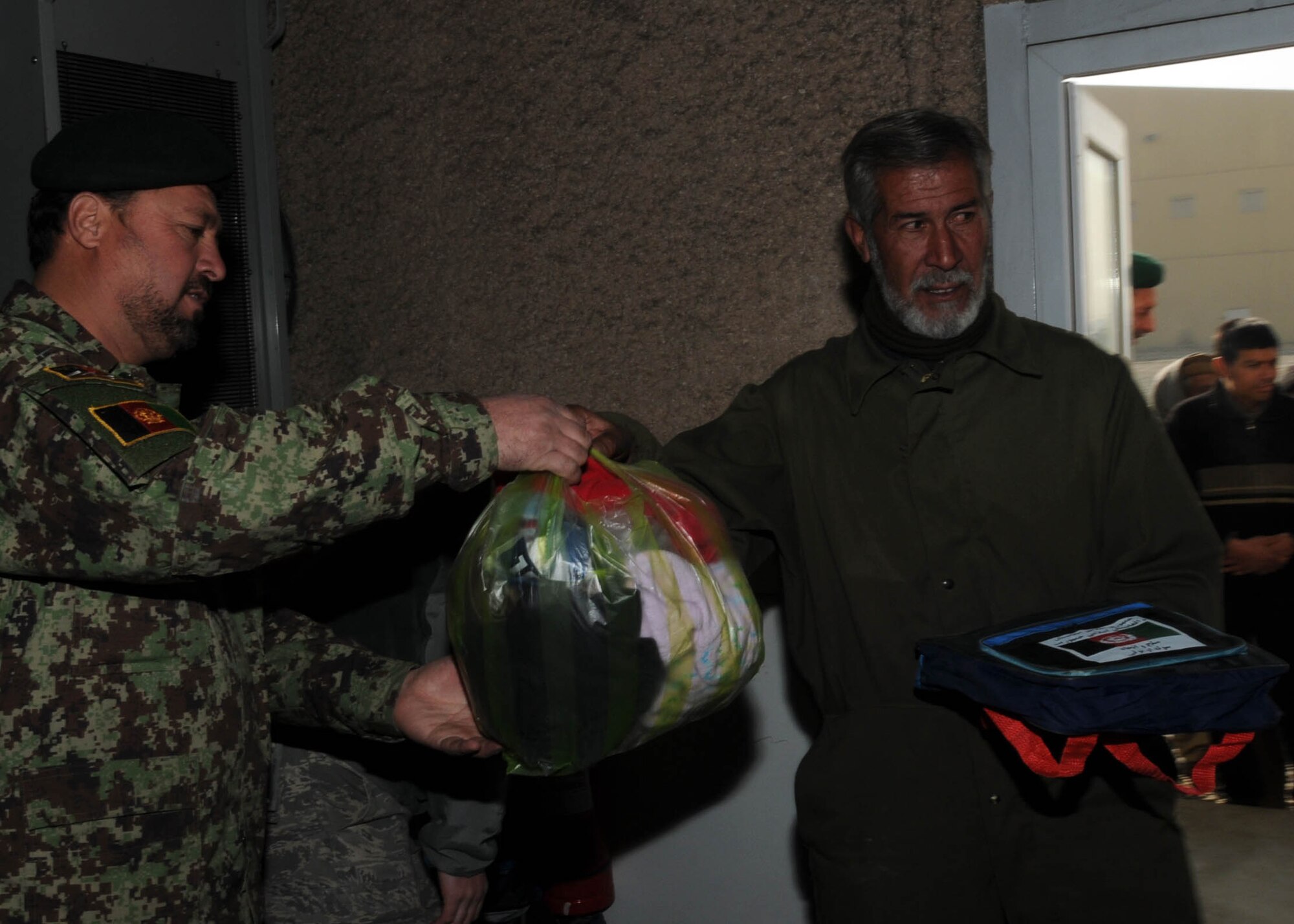 KABUL, Afghanistan - An Afghan contractor receives goods from a member of the Afghan Air Force on the Afghan Air Force Base in Kabul, Afghanistan Jan. 5. (U.S. Navy photo by Mass Communications Specialist 3rd class Petty Officer Jared E. Walker/ RELEASED).