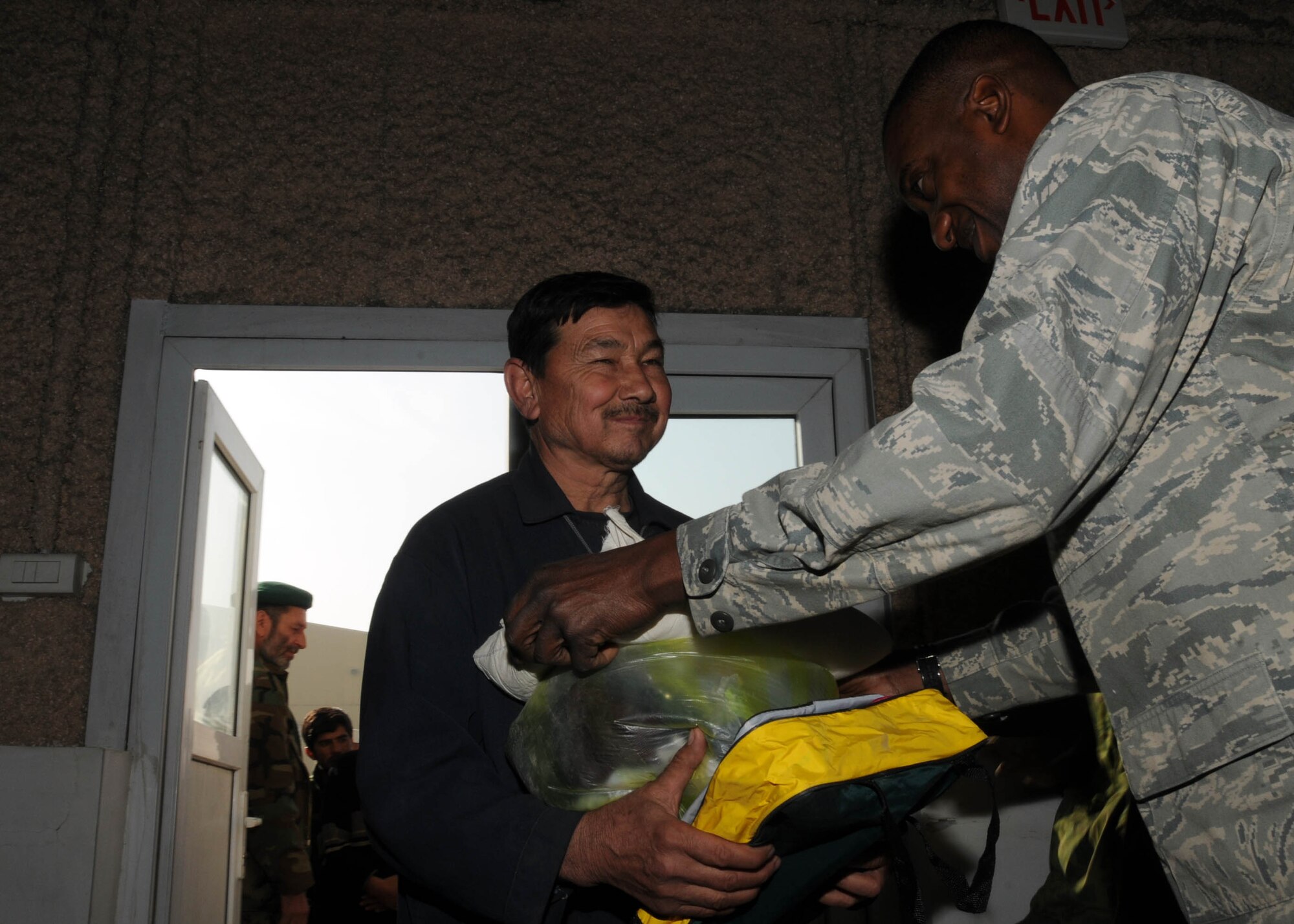 KABUL, Afghanistan - Afghan contractor receives goods from Lt. Col. Samuel Lightfoot, an advisor from the 438th Air Expeditionary Wing, on the Afghan Air Force Base in Kabul, Afghanistan Jan. 5. (U.S. Navy photo by Mass Communications Specialist 3rd class Petty Officer Jared E. Walker/ RELEASED).