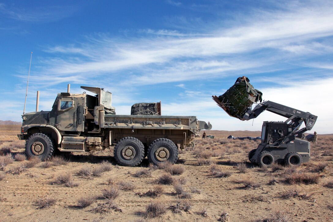 A U.S. Navy bobcat lifts a pallet of supplies into the back of a dump truck during Operation Koranai Permakhtag at Bora Jengi checkpoint, Zabul province, Afghanistan, Dec. 25, 2010.